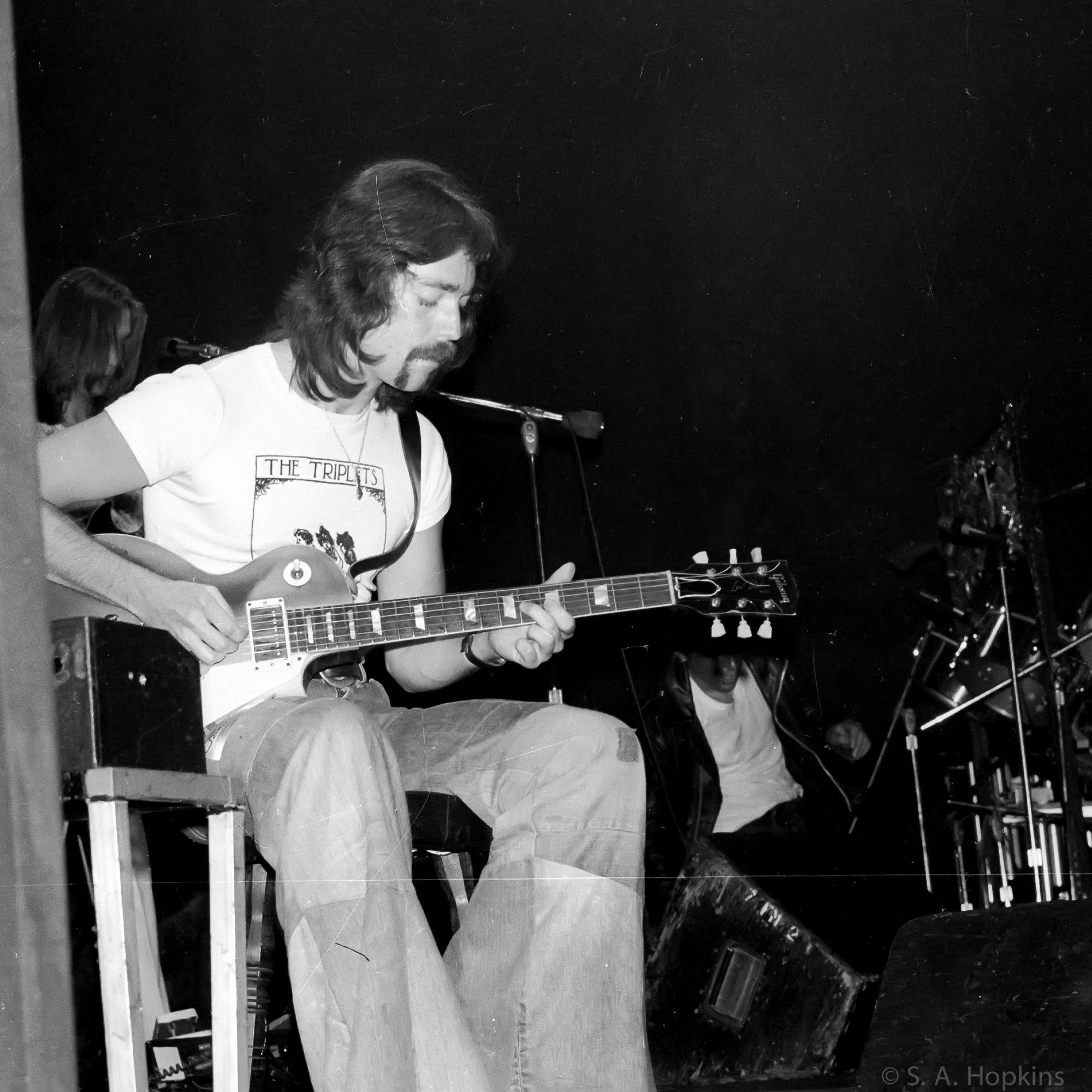 Black and white photograph of Steve Hackett, Genesis guitarist, on stage.