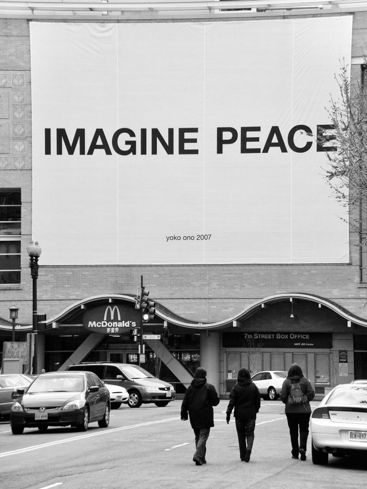 A large sign that reads Imagine Peace is seen above a McDonald’s restaurant on a DC street. The work is by Yoko Ono.