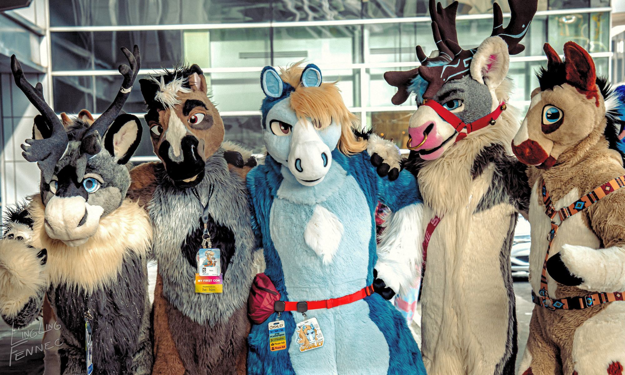 A photo of several fursuiters under the canopy of the main entrance to the Anthro New England Westin. From left to right, there's a grey caribou, a brown and grey horse, a blue pegasus, a grey and white caribou, and a light tan horse, all standing with linked arms and facing the camera for a group picture.