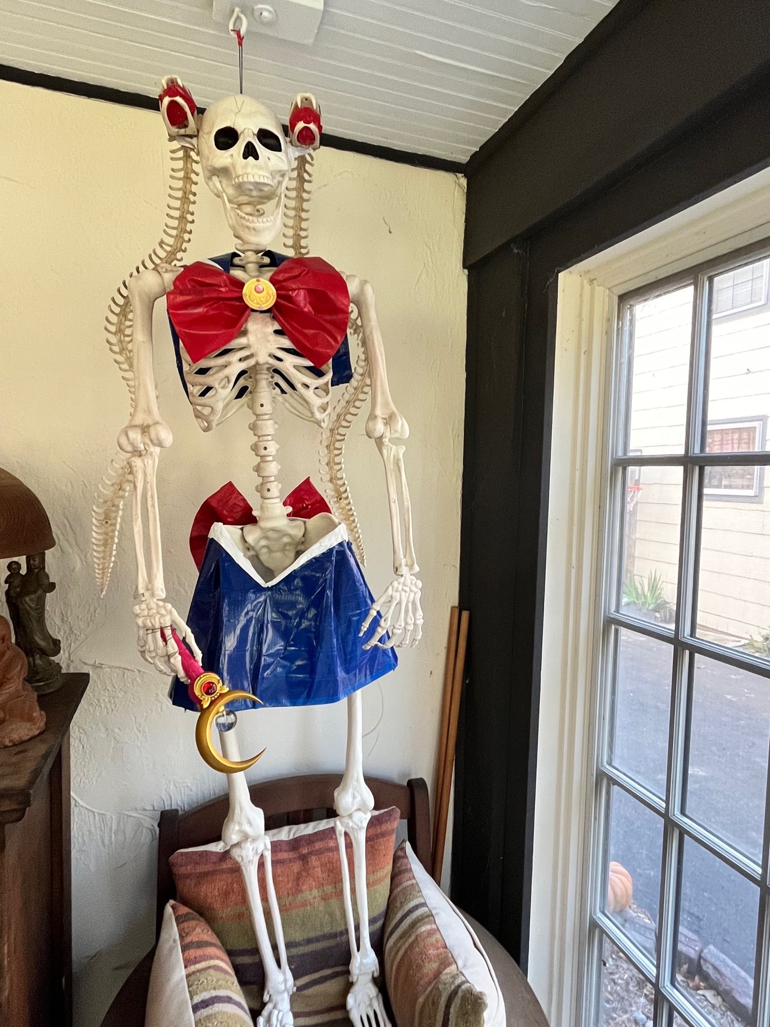 Image of a Halloween decoration full size skeleton in a sailor moon costume made of duct tape. Her iconic pigtails are also made out of bone snakes that are attached to her skull and holding her hairpieces. 