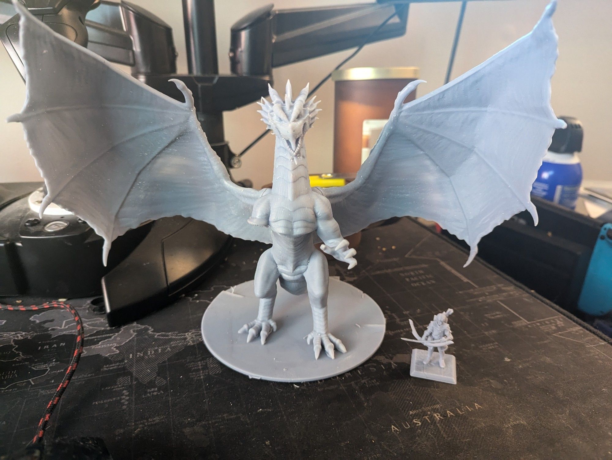 Unpainted resin 3D prints of an ancient red dragon next to a human fighter with a longbow