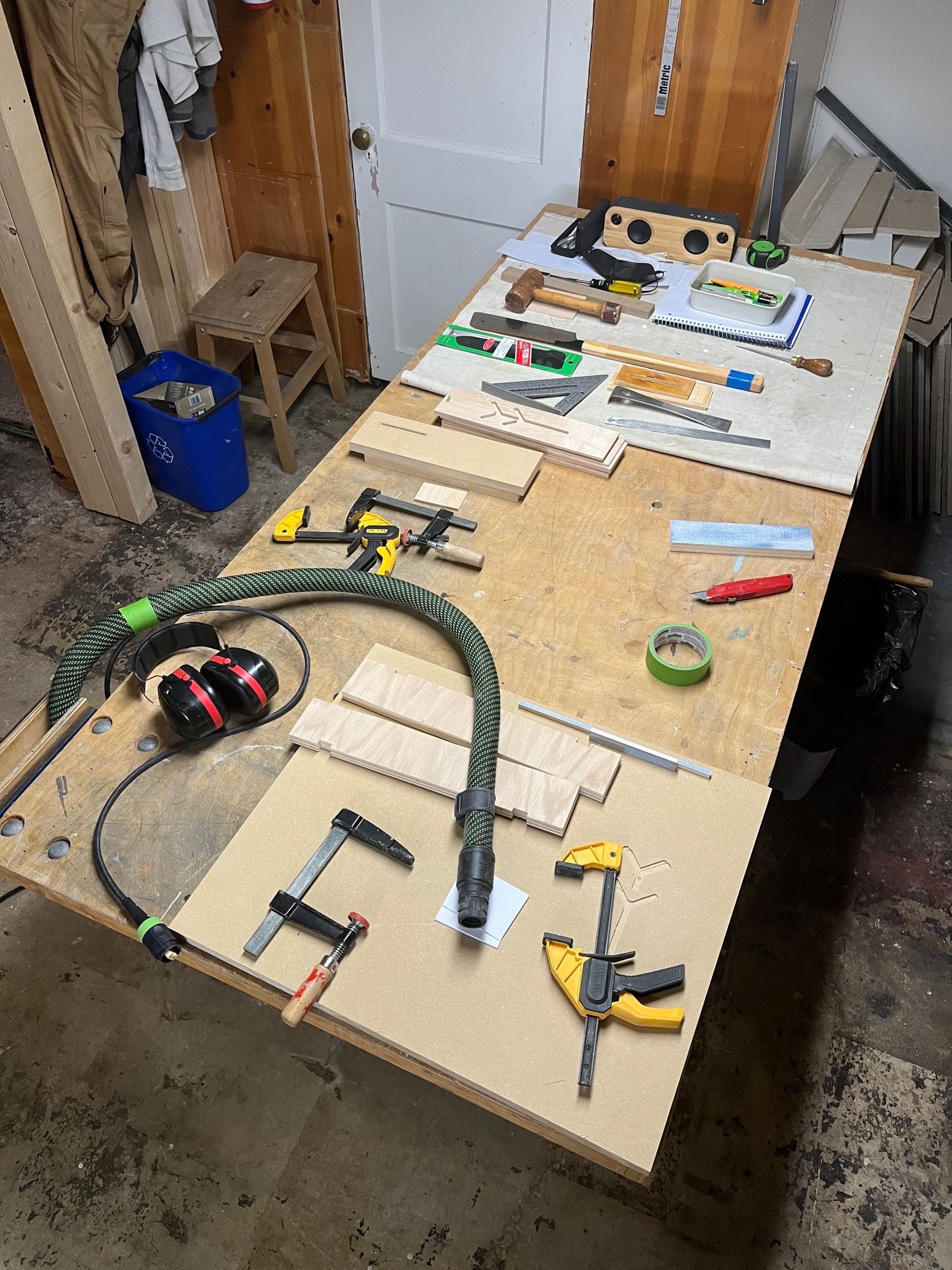 Overhead view of my workbench. It’s covered in hand tools, maybe 20-30: clamps, knive, saw, chisels, blocks of wood, and more. Everything is laid out mostly in order and lined up.