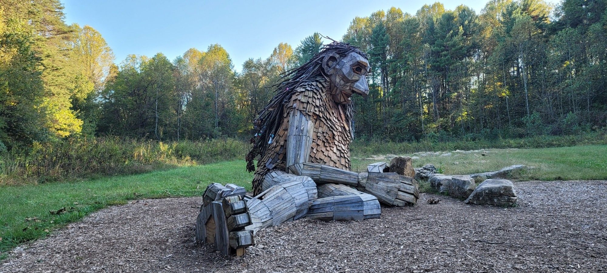 A large wooden statue of a troll laying on its legs