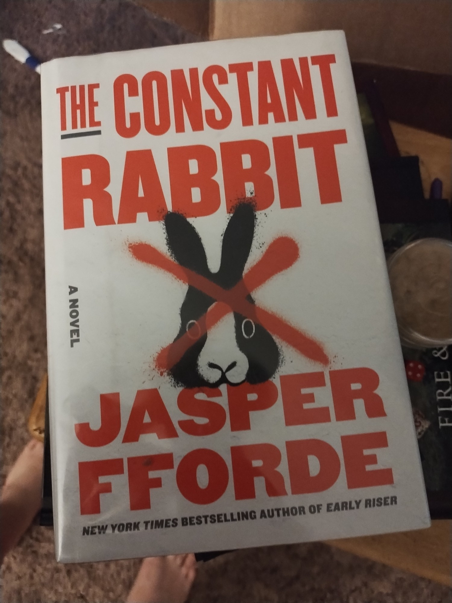 A hardback library copy of Jasper Fforde's "The Constant Rabbit".   The cover art is a graffiti rabbit face with a red X over the top.