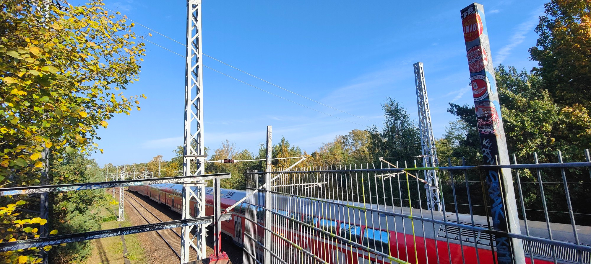 Blue sky next to train tracks as a red regio bahn train passes