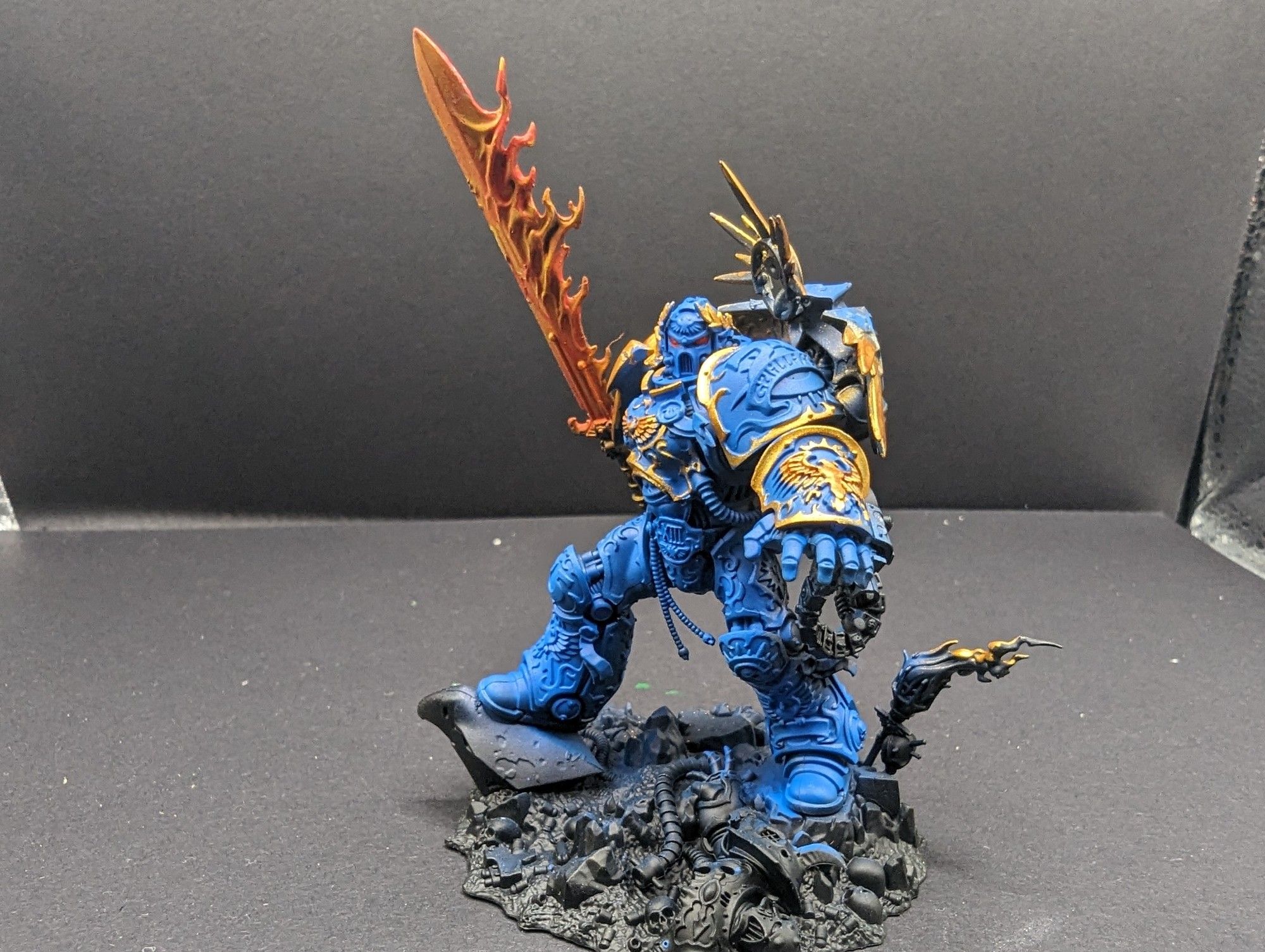 A shot of guilliman model with gold accents and red eyes, the shot is from the side so you can see his gauntlet