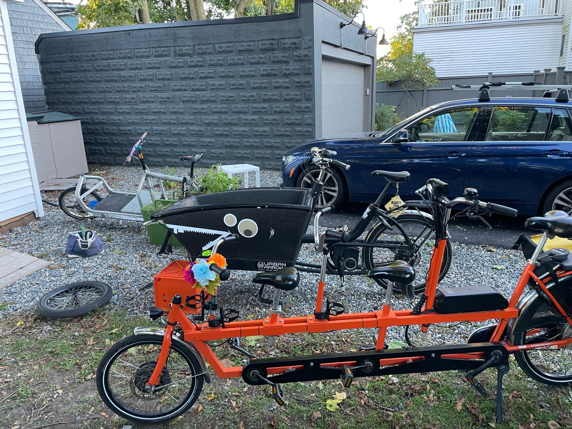 Three cargobikes sitting in front of a car