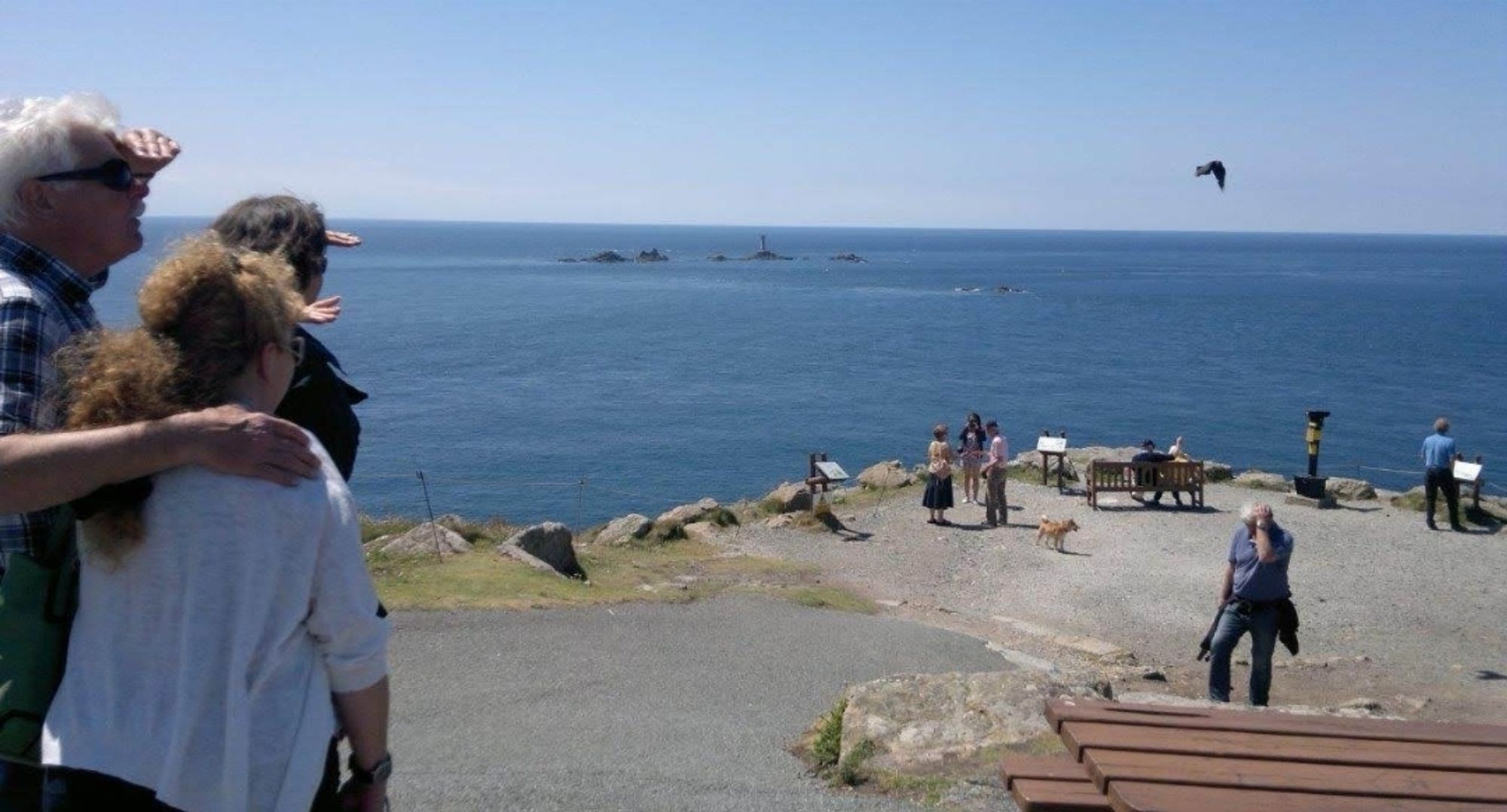 Der suchende Blick von drei Personen geht von einer Landspitze über das Meer Richtung Horizont