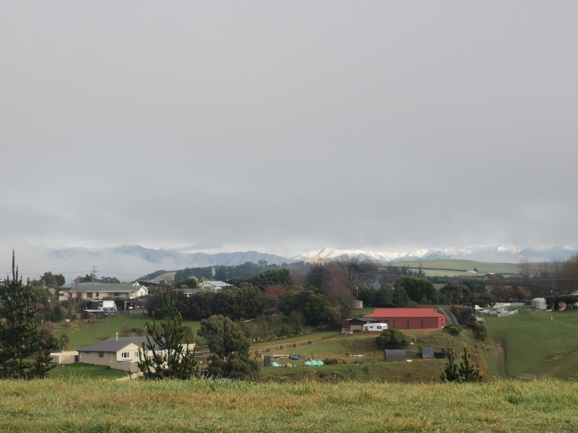 Heavy grey cloud layer revealing snowy mountains in the distance.