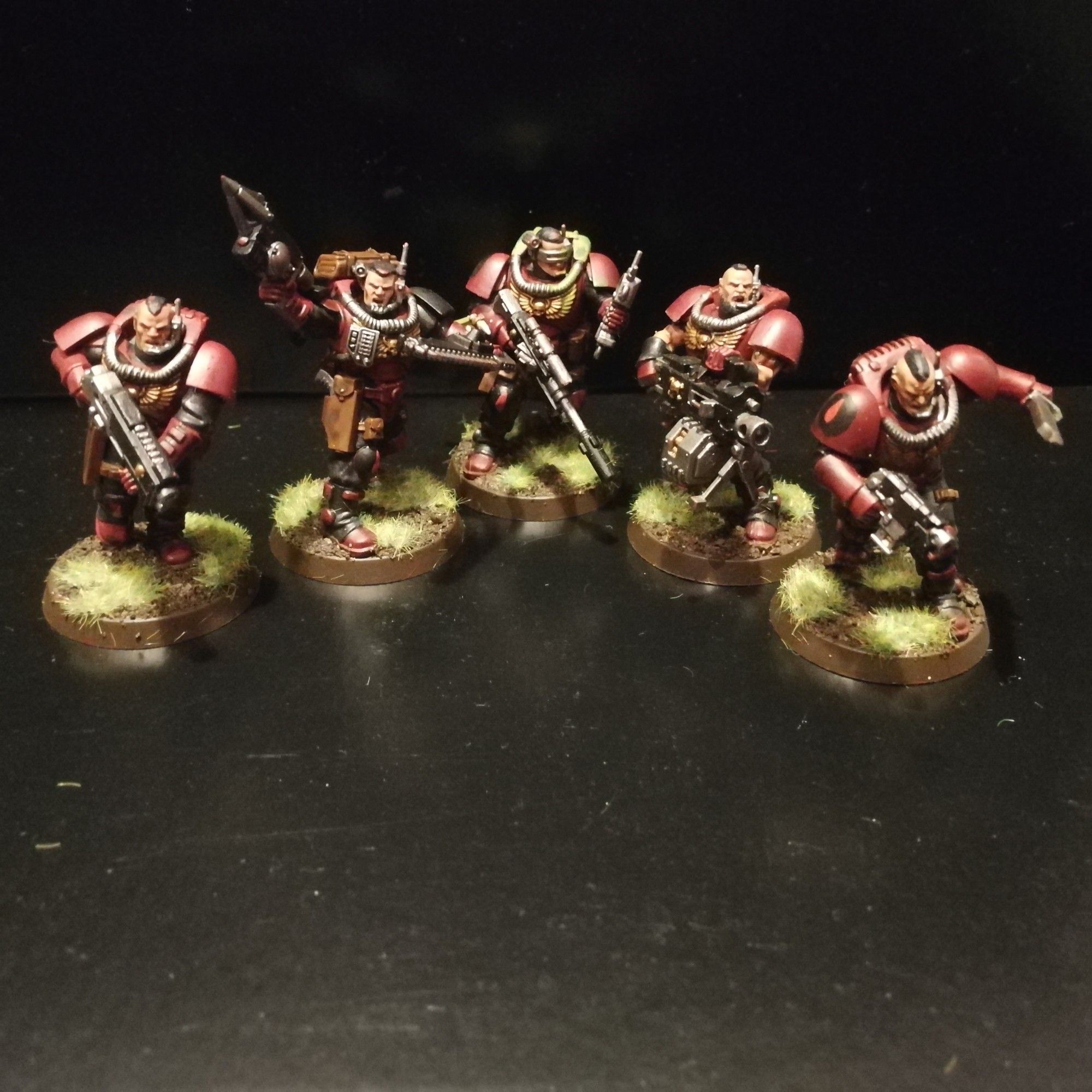 A squad of 5 Space Marine Scouts painted as Angels Encarmine consisting of a Sergeant with grapnel gun and chainsword, and 4 Scouts, onr with shotgun, one with sniper rifle, one with heavy bolter, and one with combat knife and bolt pistol.