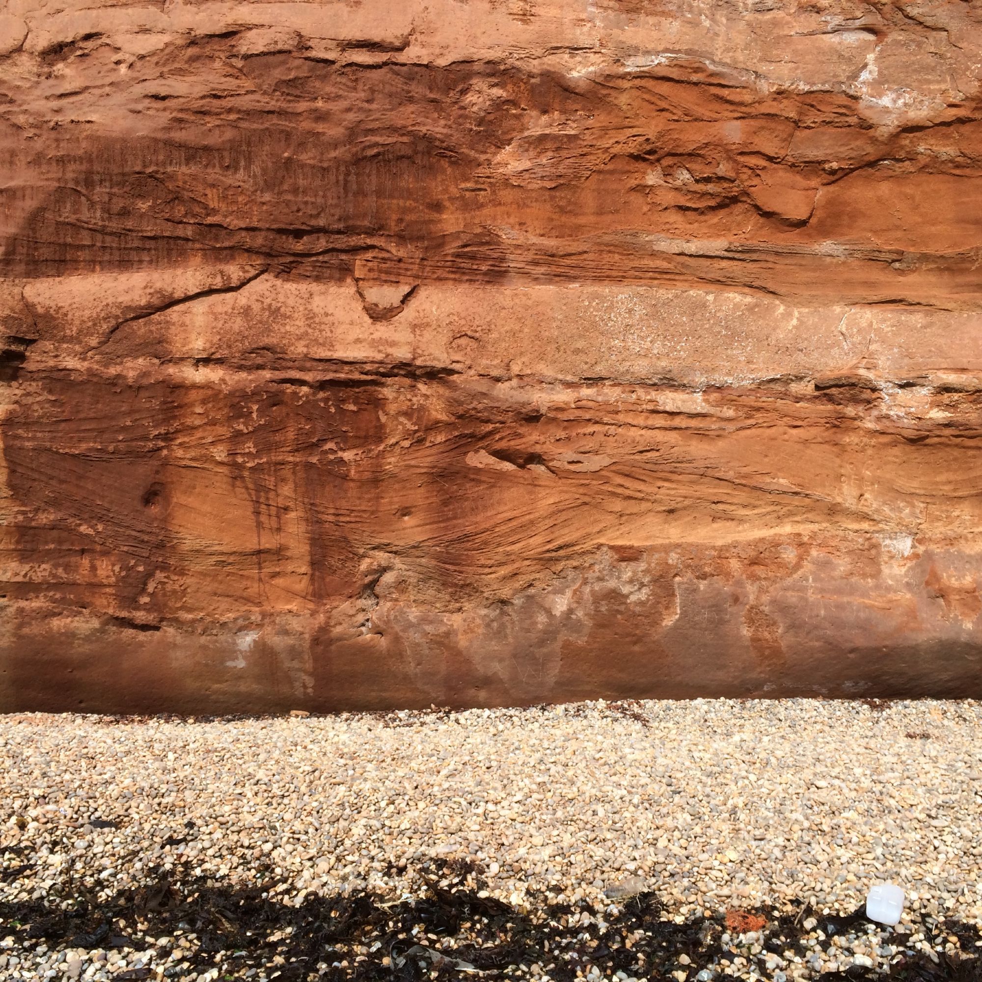 Red cross bedded sandstone with a pebble beach in foreground