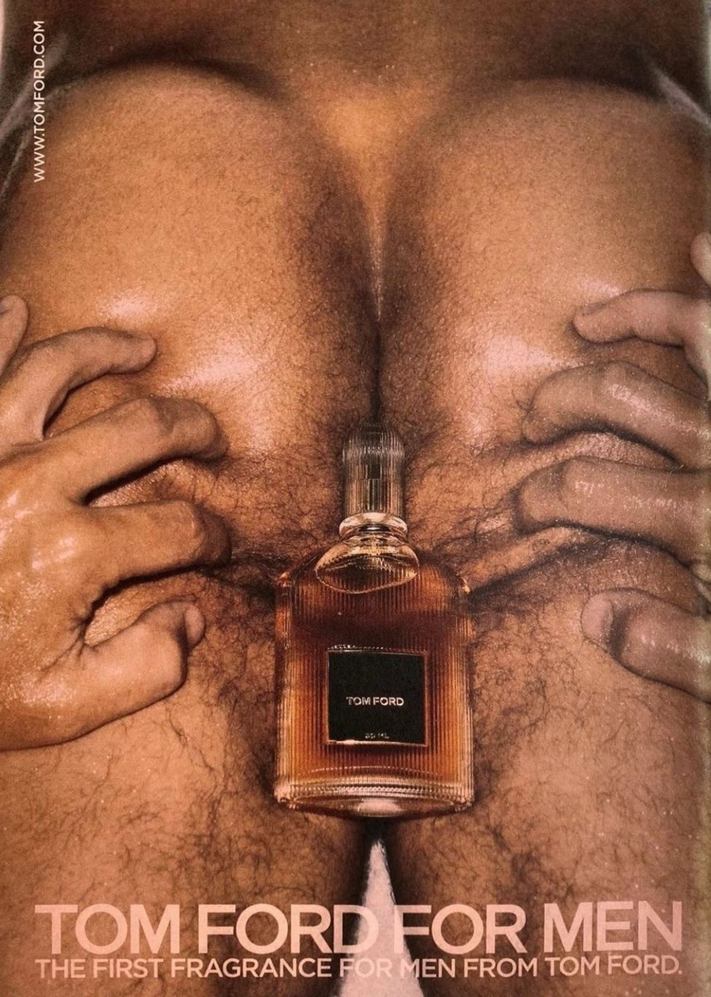 in a closeup photograph for an advertisement, hands spread hairy butt cheeks wherein rests a bottle of cologne. text at the bottom reads "tom ford for men: the first fragrance for men from tom ford."