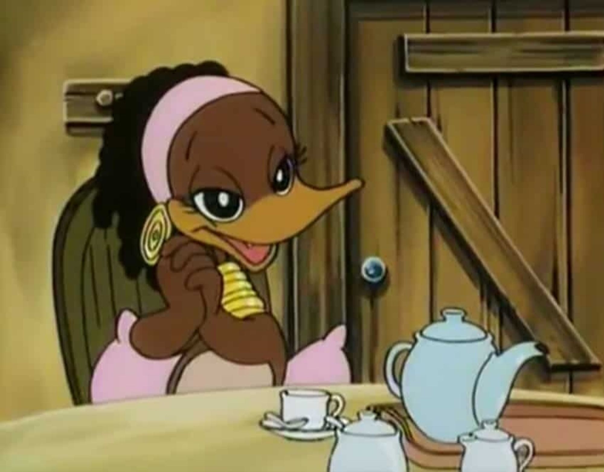 Winney Wana, a character from the cartoon series Alfred J. Kwak, sitting at a table in a cozy wooden cottage, having tea.

She is a brown duck woman dressed with a pink ribbon around her hindquarters and a pink headband, as well as gold spiral earrings and bands of gold running up the near total length of her neck. She also has curled, dreadlocked hair. Her doe eyes are large and half-lidded as she speaks with someone off-screen.