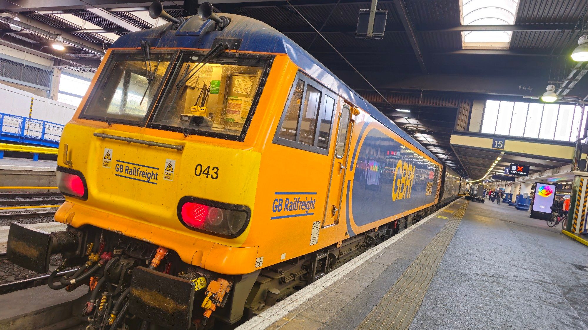 Class 92 loco 92043, in orange and dark blue GBRf livery, rests at the buffer stops at London Euston station after hauling the Highland Caledonian Sleeper.