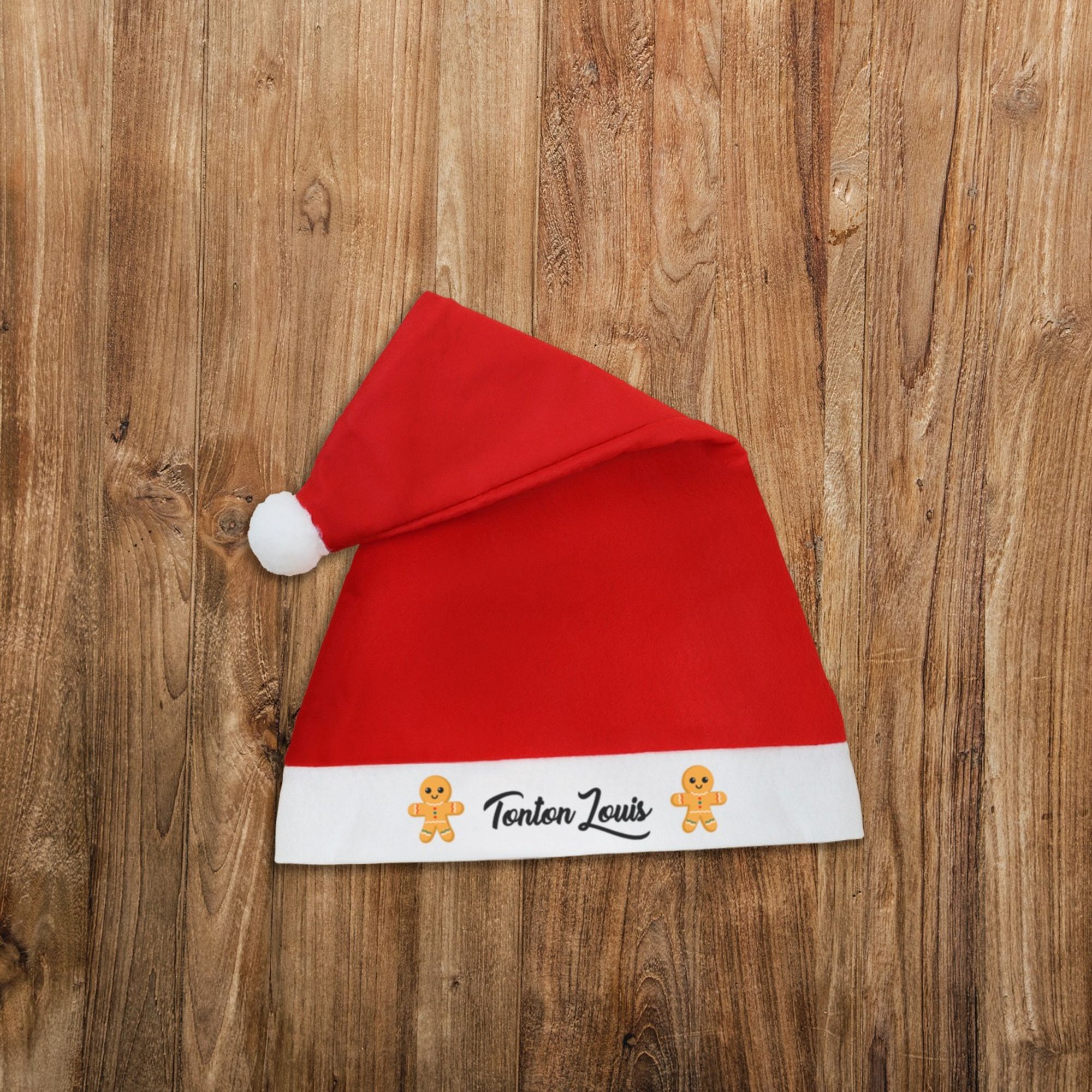 Bonnet de Noël rouge avec un pompon blanc et personnalisé avec le prénom de votre choix entouré de petits bonshommes de pain d'épices.