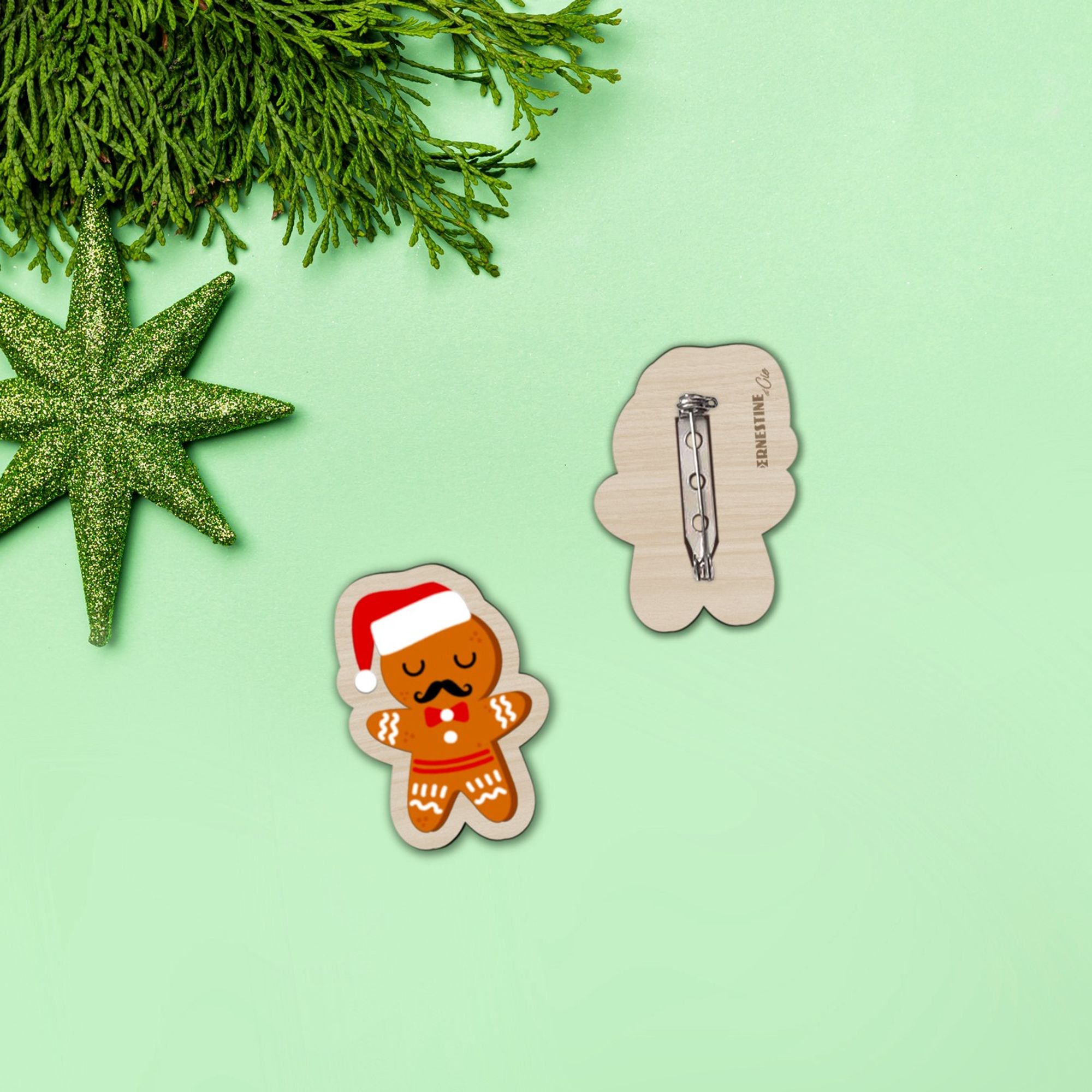 Broche en bois imprimée d'un petit bonhomme en biscuit de Noël avec un bonnet et des moustaches.