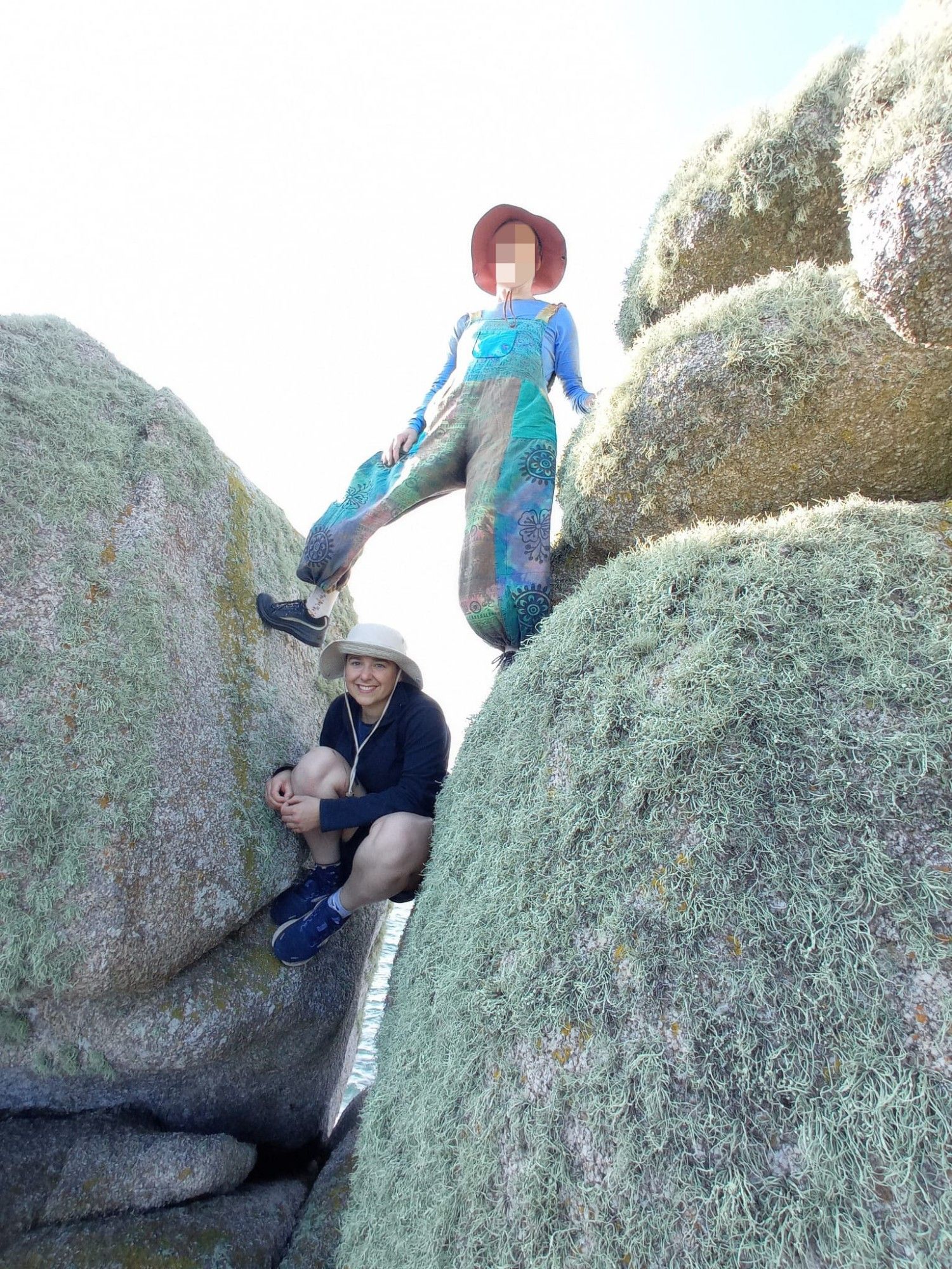 My mum, wearing turquoise dungarees and a hat, casually straddling the gap between two boulders. I am wedged beneath her in the gap.