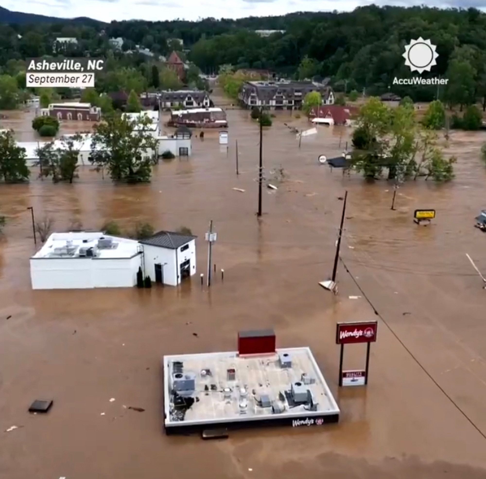 Asheville, NC devastated by flood waters after Hurricane Helene. In the foreground is a Wendy’s restaurant covered nearly to its roof by water.