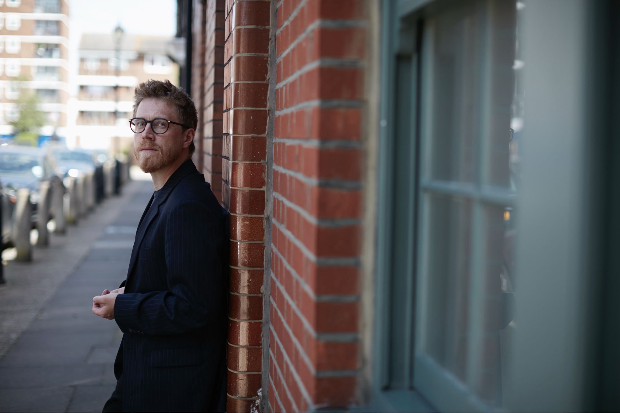 Me looking like a ingenue artistic director of the Young Vic all in black with glasses leaning against a wall