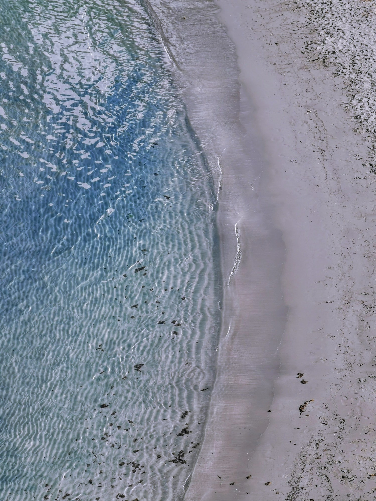 Blaues klares Wasser und weißer Sand, fast senkrecht von oben aufgenommen 