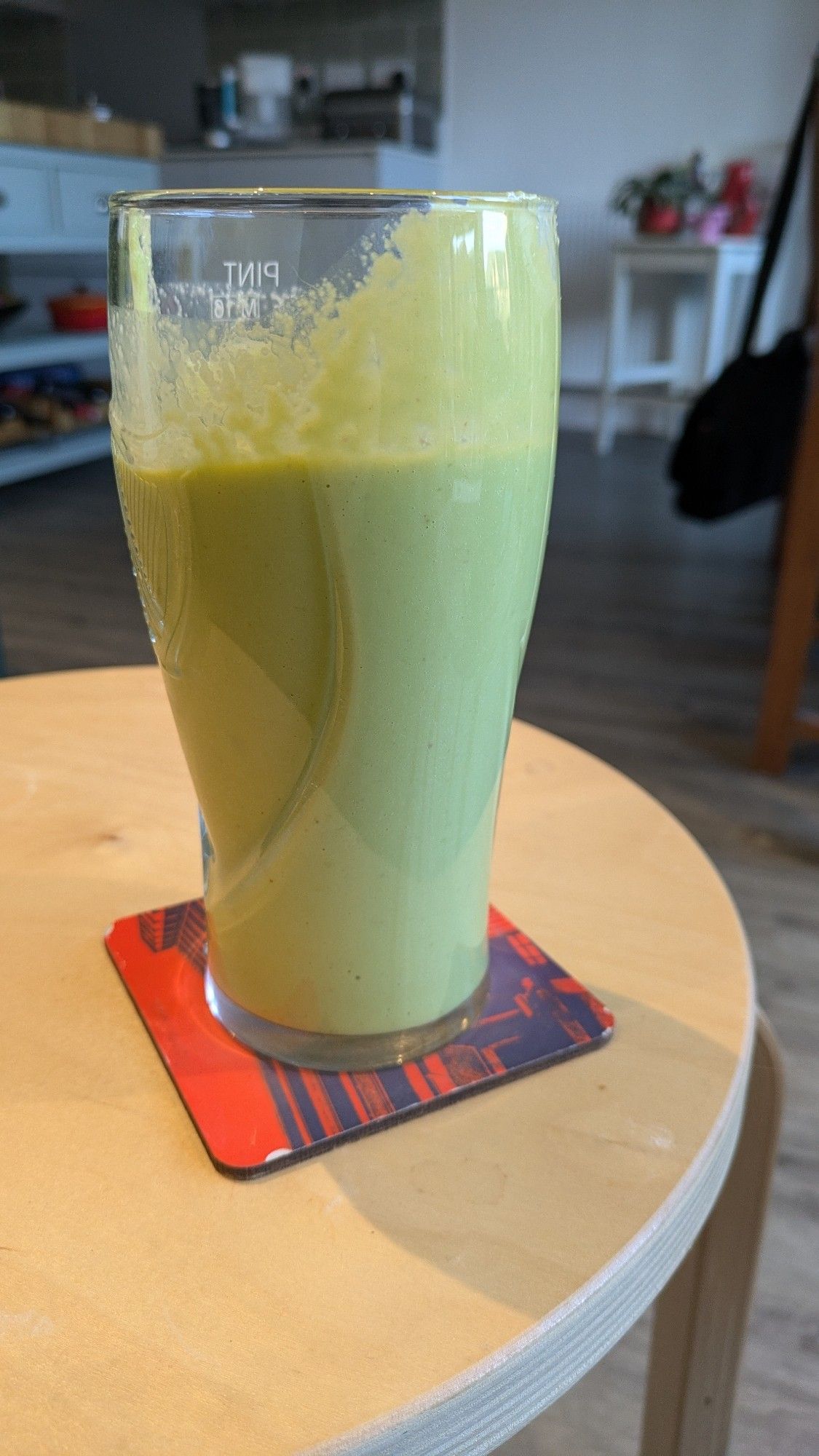 A green coloured smoothie in a pint glass.