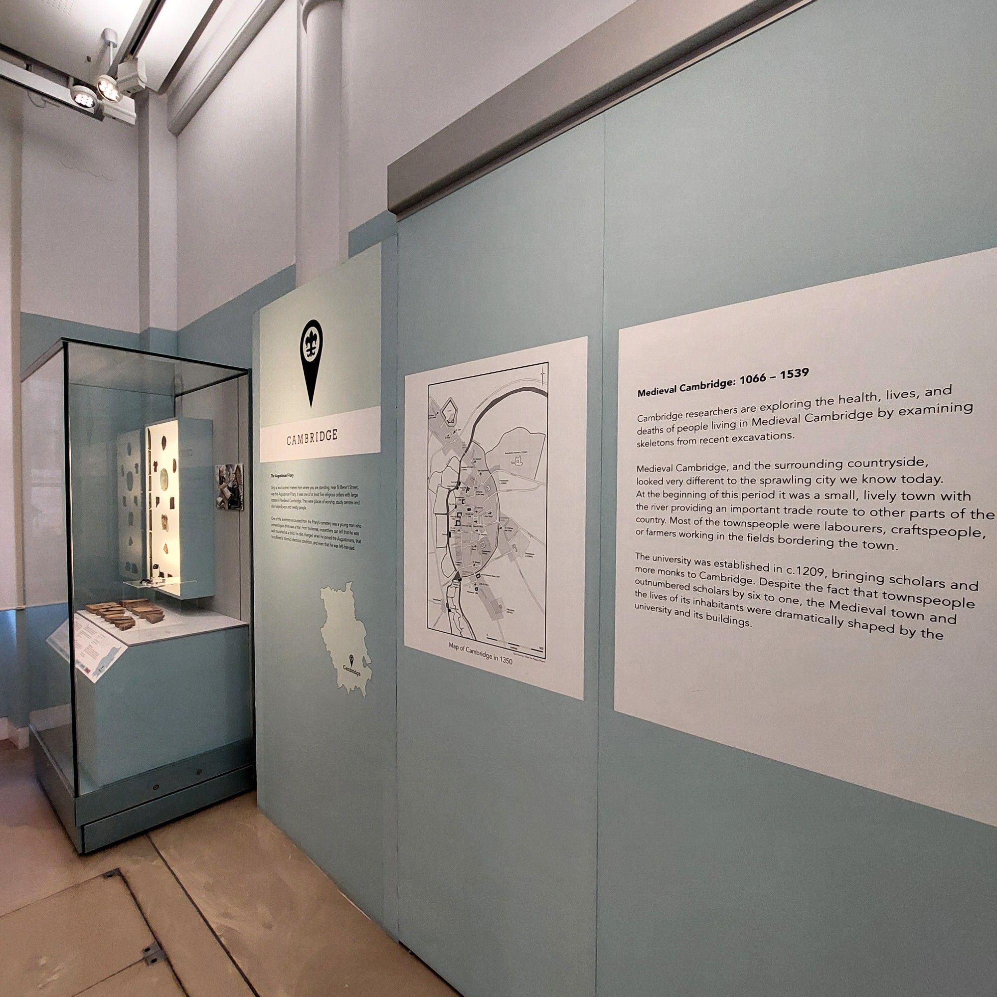 A photograph of an exhibit displaying medieval artefacts from an Augustinian Friary found in the centre of Cambridge. The display includes a map and further information about medieval Cambridge 1066-1539.