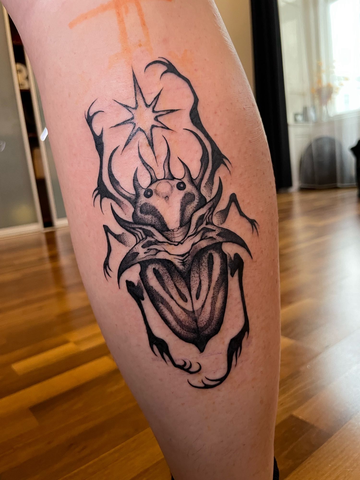 Darksurreal blackwork bug tattoo on a leg.