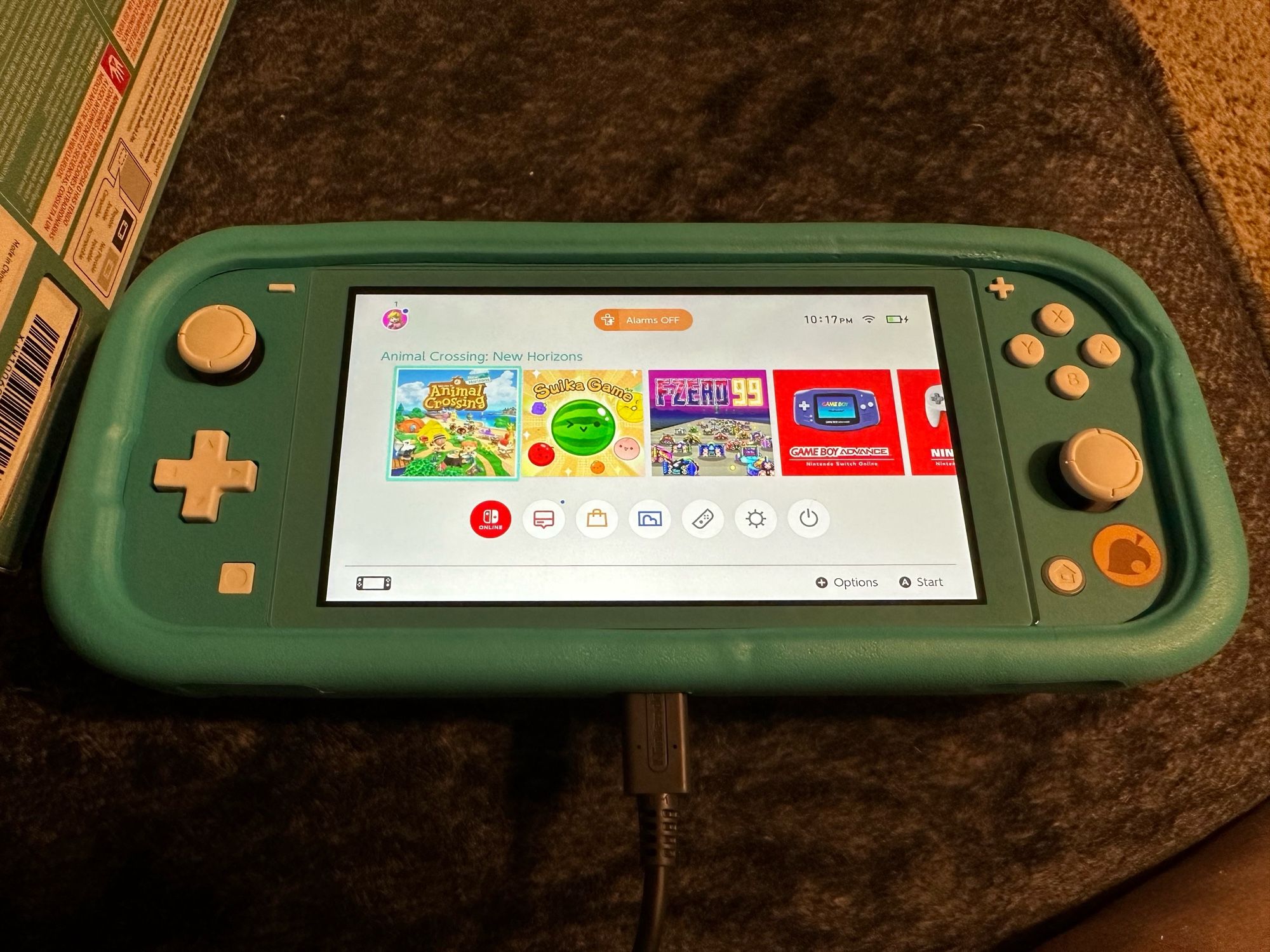 Turquoise Nintendo Switch Lite Animal Crossing edition in a matching case sitting on a gray couch