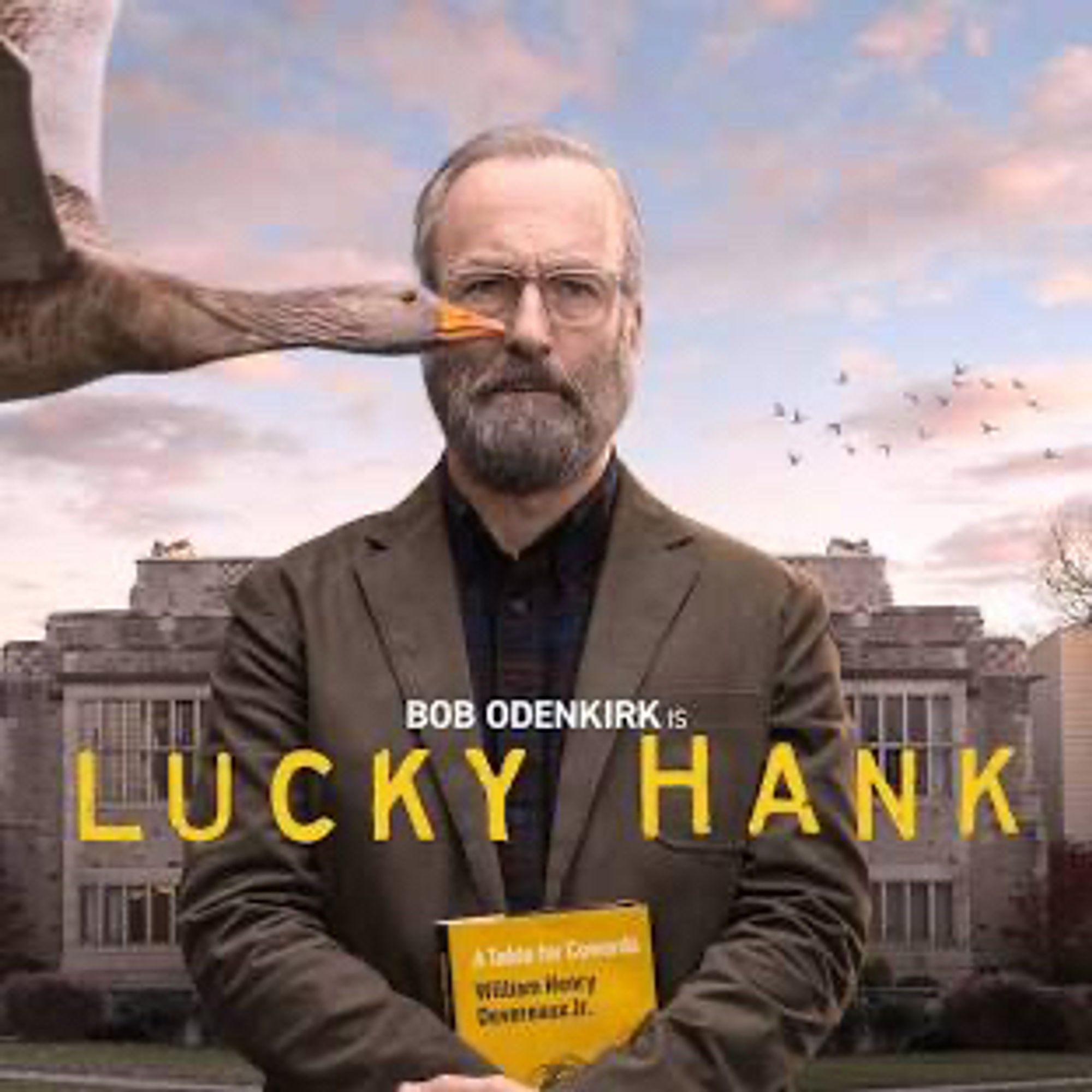 Bob Odenkirk as Lucky Hank, a photo of him holding a book his character William Henry "Hank" Devereaux, Jr has written called A Table for Cowards in front of a University building, while a goose is flying through the frame, about to fly into Hank's nose.