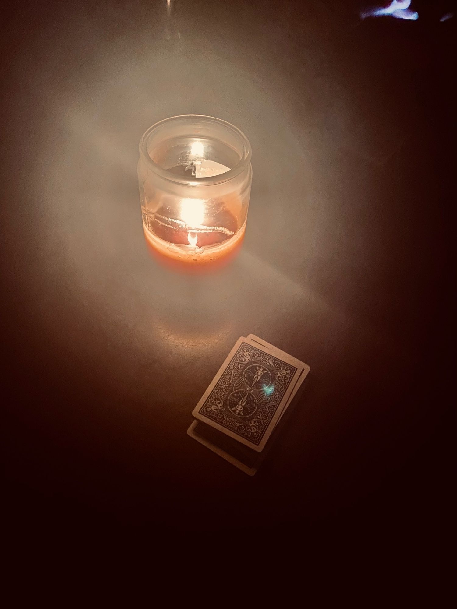 A card deck illuminated by a candle on a table.