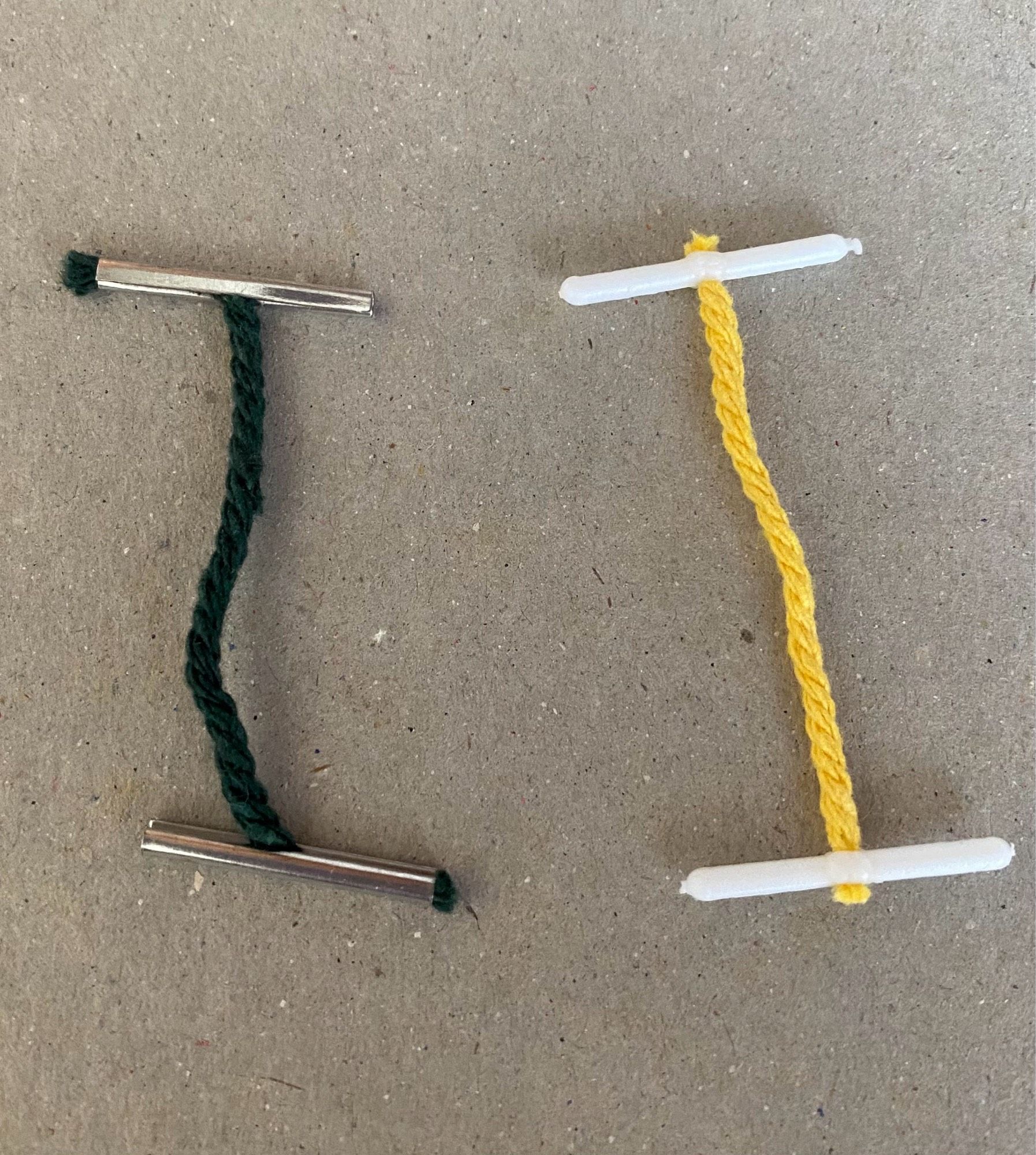 Green string metal tipped tag on left, yellow string plastic tag on right