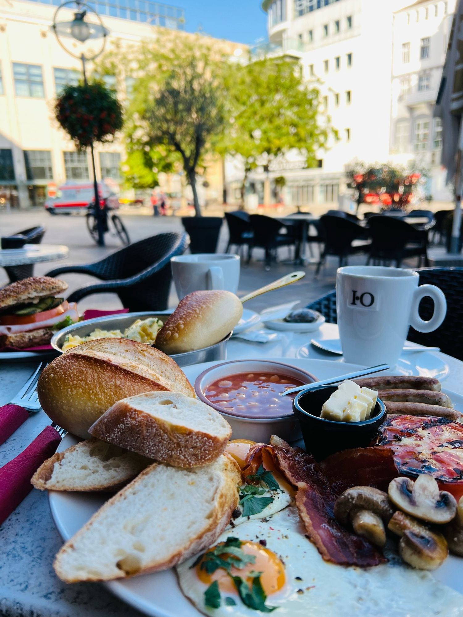 Ein englisches Frühstück mit Ei, Würstchen, Baked Beans, gebratenen Champignons und Tomate, im Hintergrund unscharf die Dortmunder City