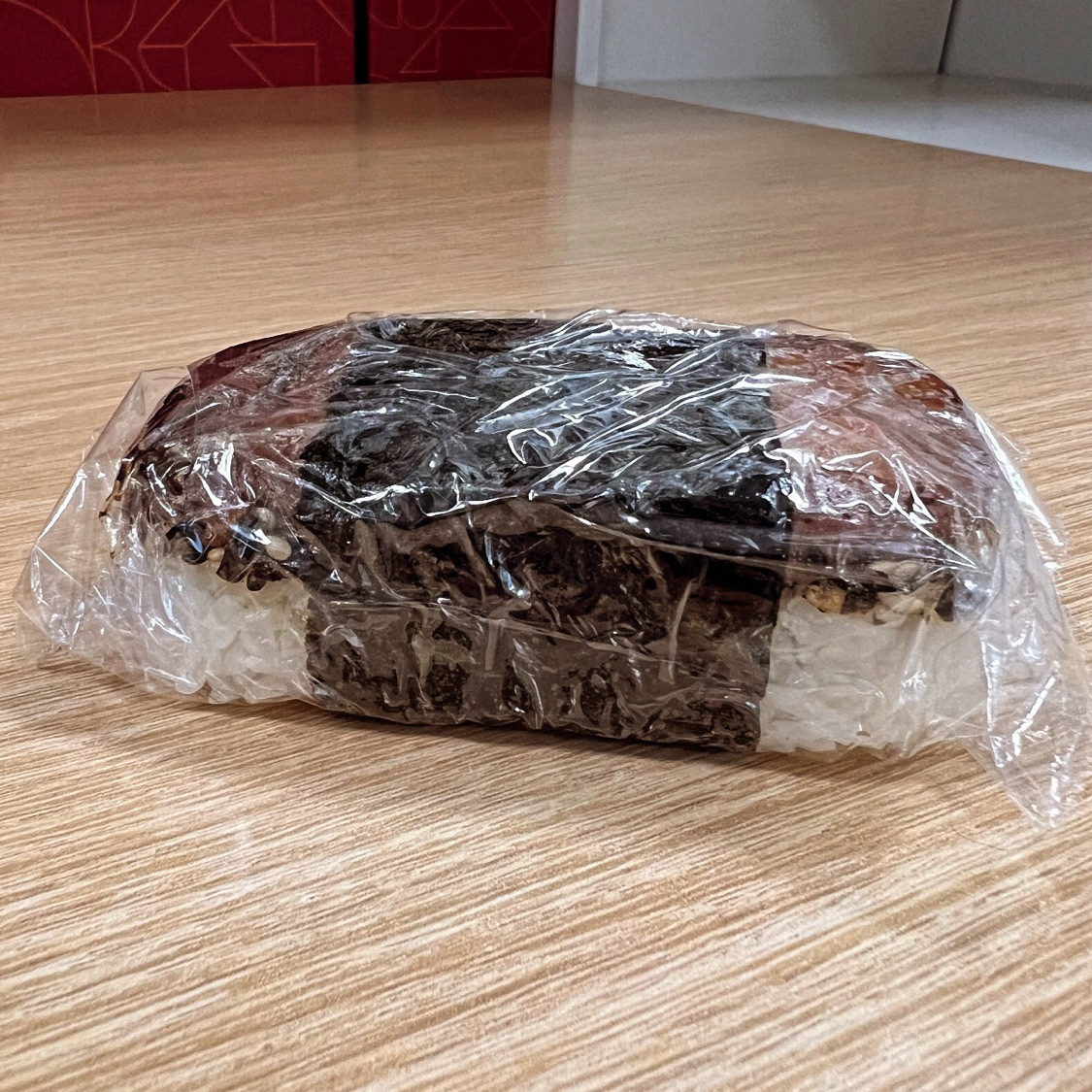 A single spam musubi wrapped in plastic wrap.