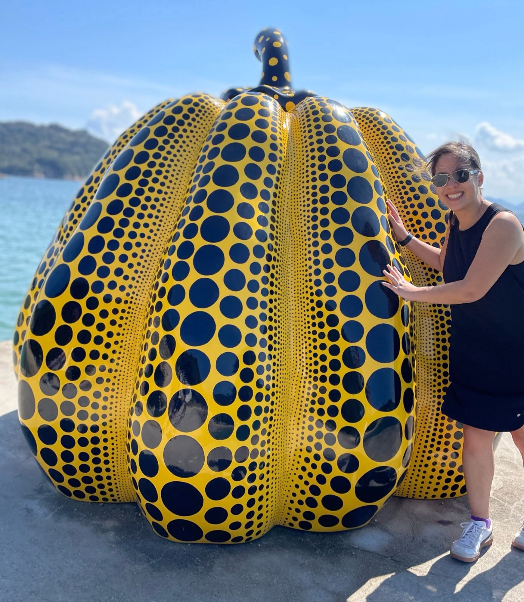 Woman posting with a yellow pumpkin covered in dots of varying sizes