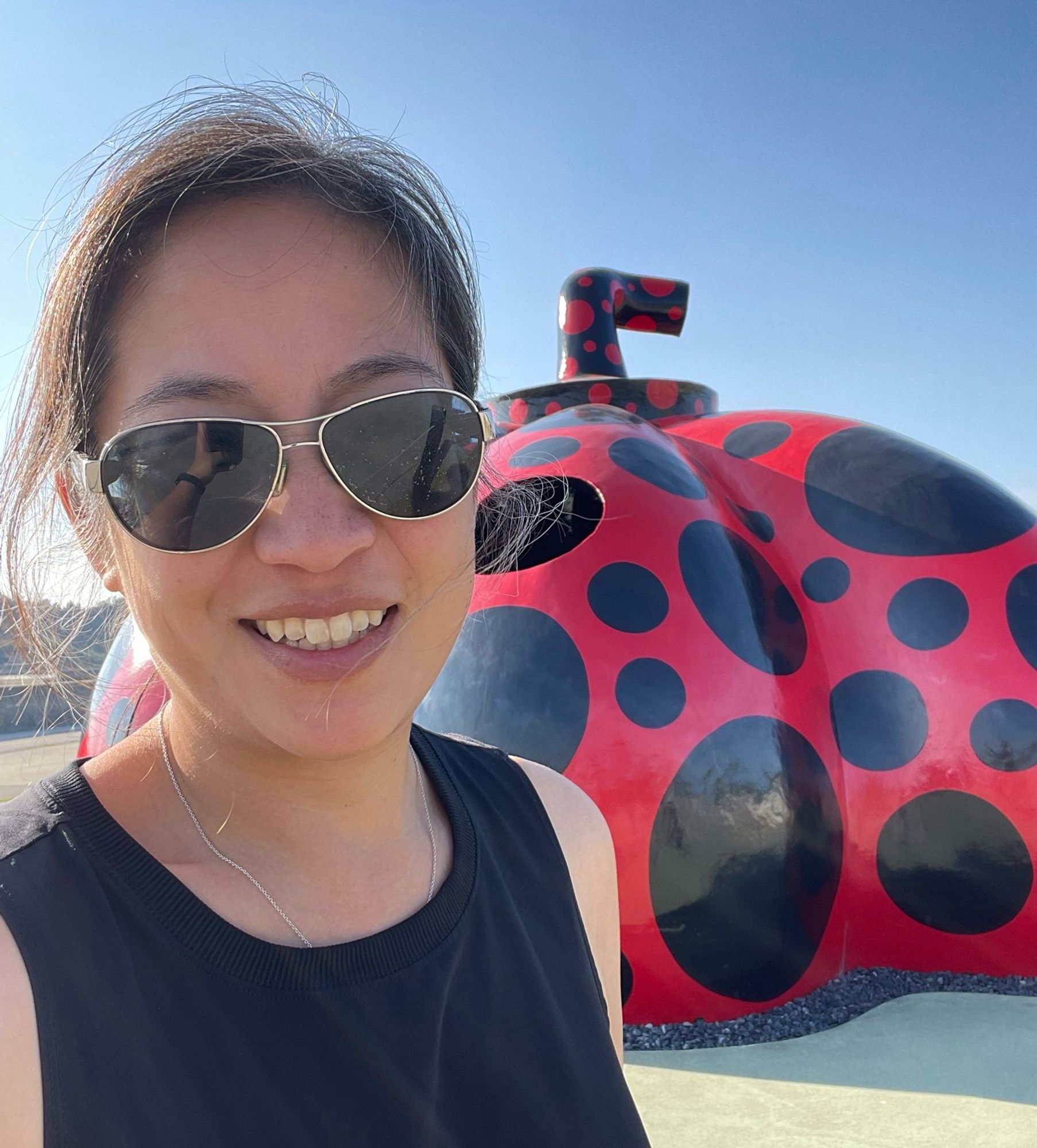 Woman in sunglasses posting in front of a red pumpkin with black polka dots