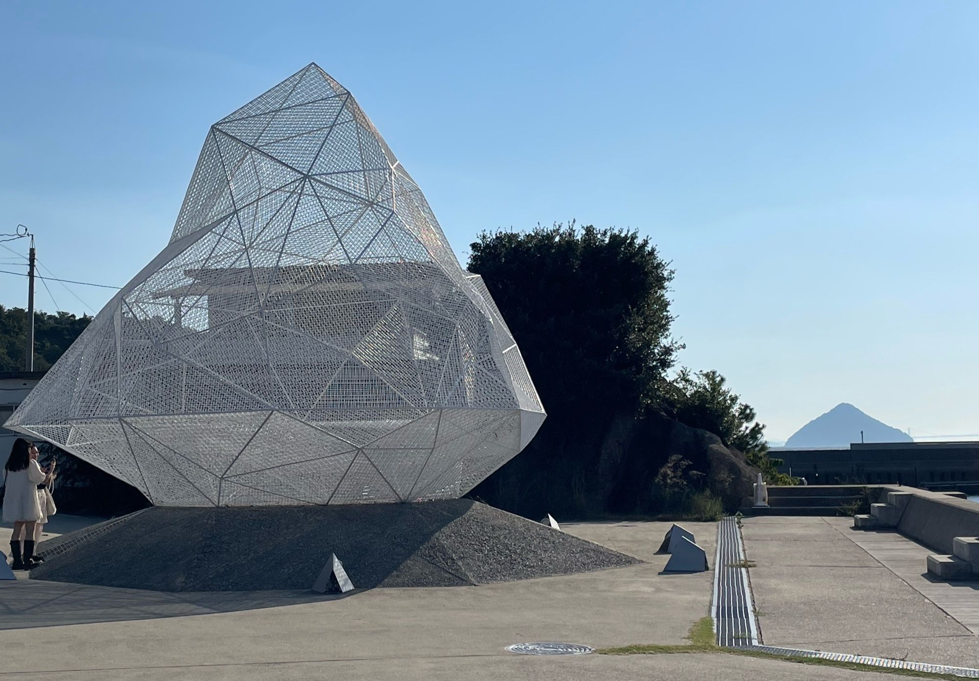 White latticed sculpture meant to show symmetry with a mountain in the distance