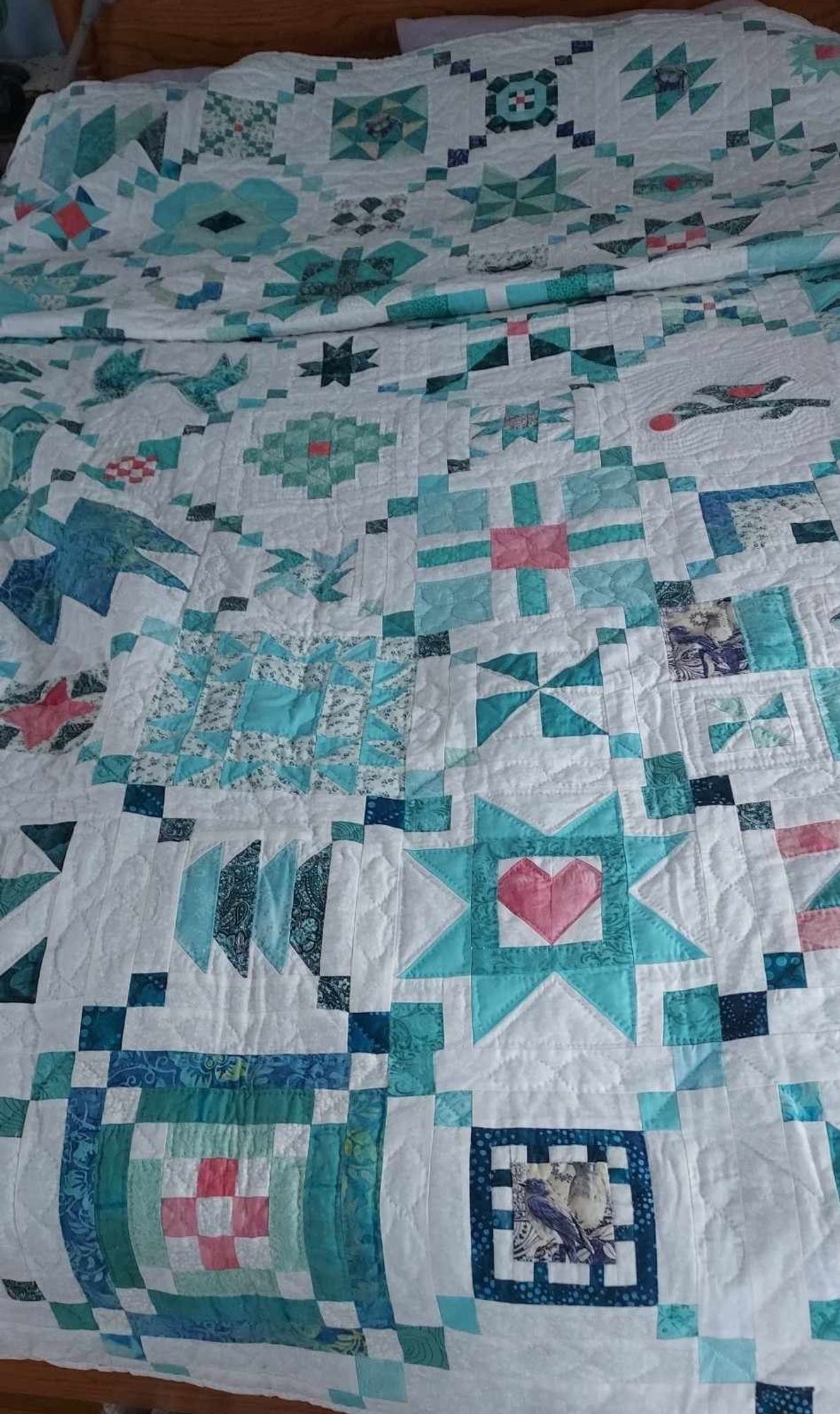 a photo of the entire blue, green, and light red quilt on a bed