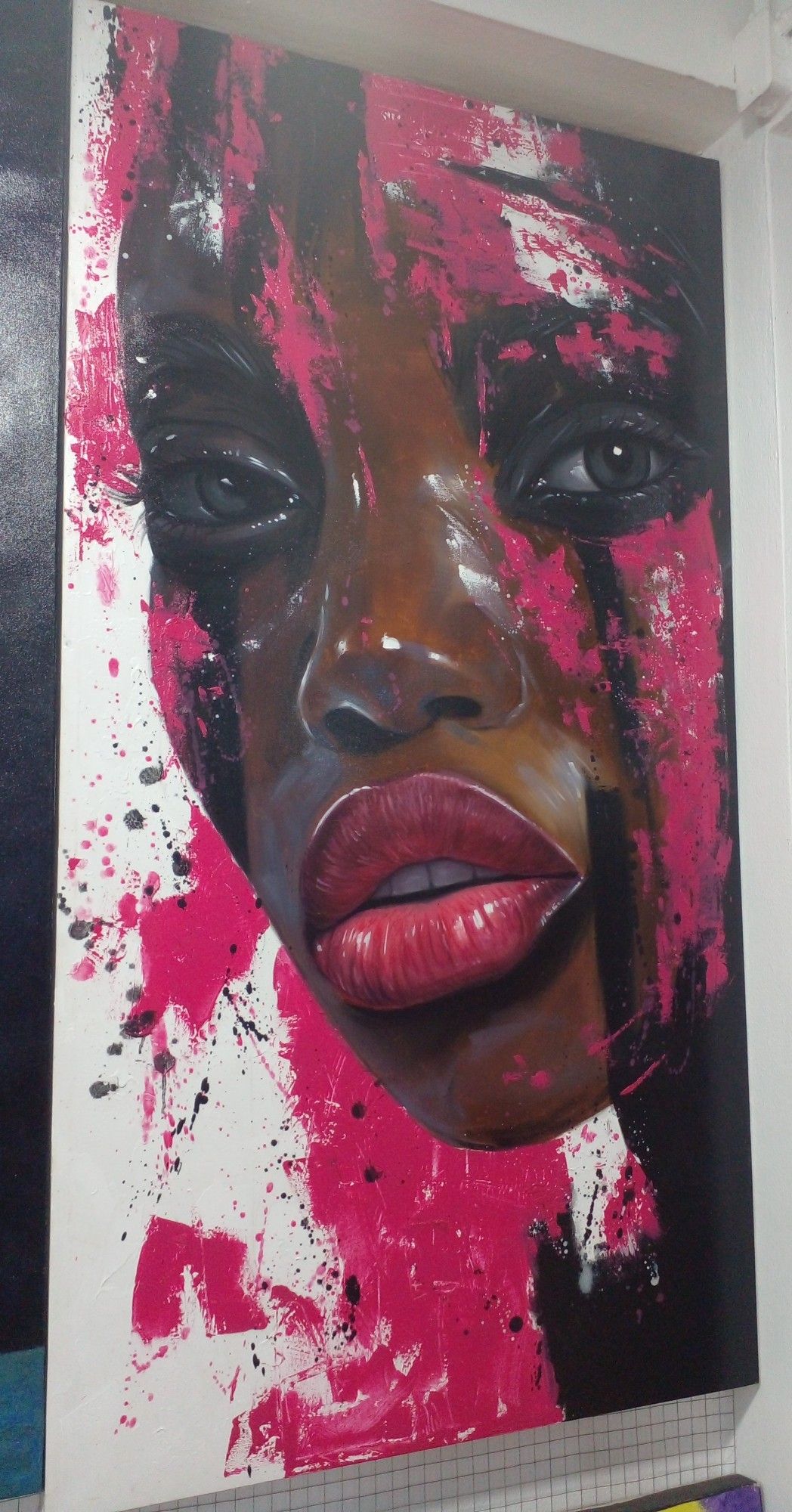 a tall narrow shaped canvas, a face looking at the viewer, pink paint running vertically down onto and around the face