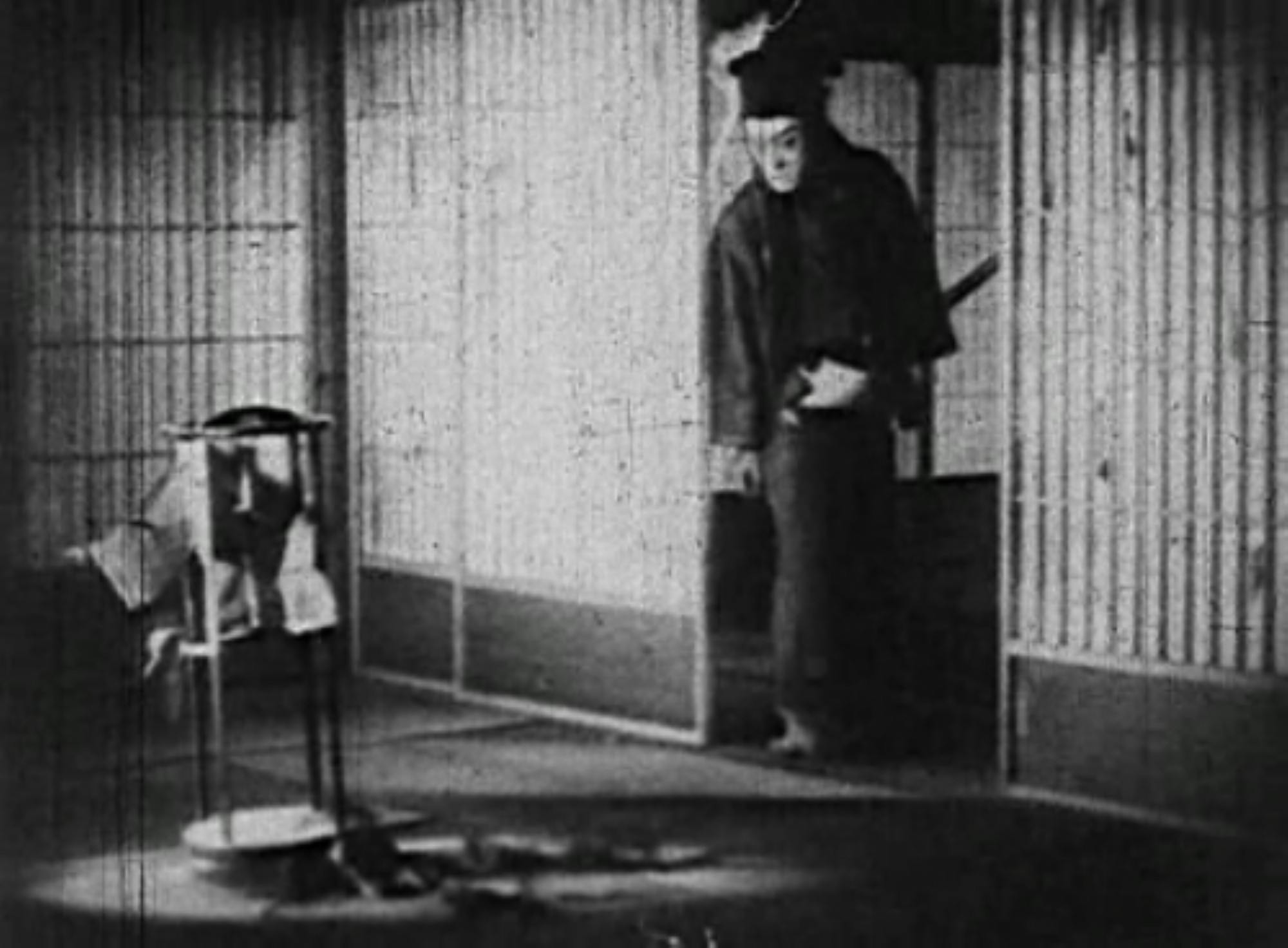 a figure in dark clothing, coming into an open doorway in a traditional japanese building, he has an angry look on his face, a sword on his hip , a black fabric hat on his head