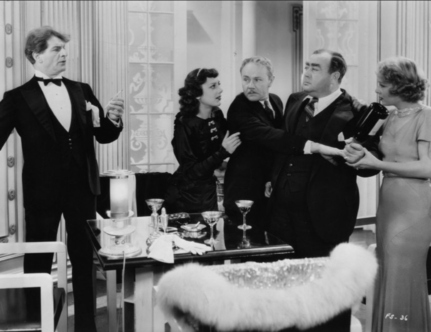 an image from the movie, a scuffle at a restaurant, the men wearing tuxedos, the women in nice dresses, they are holding back one of the women's husbands from attacking a drunk obnoxious fellow