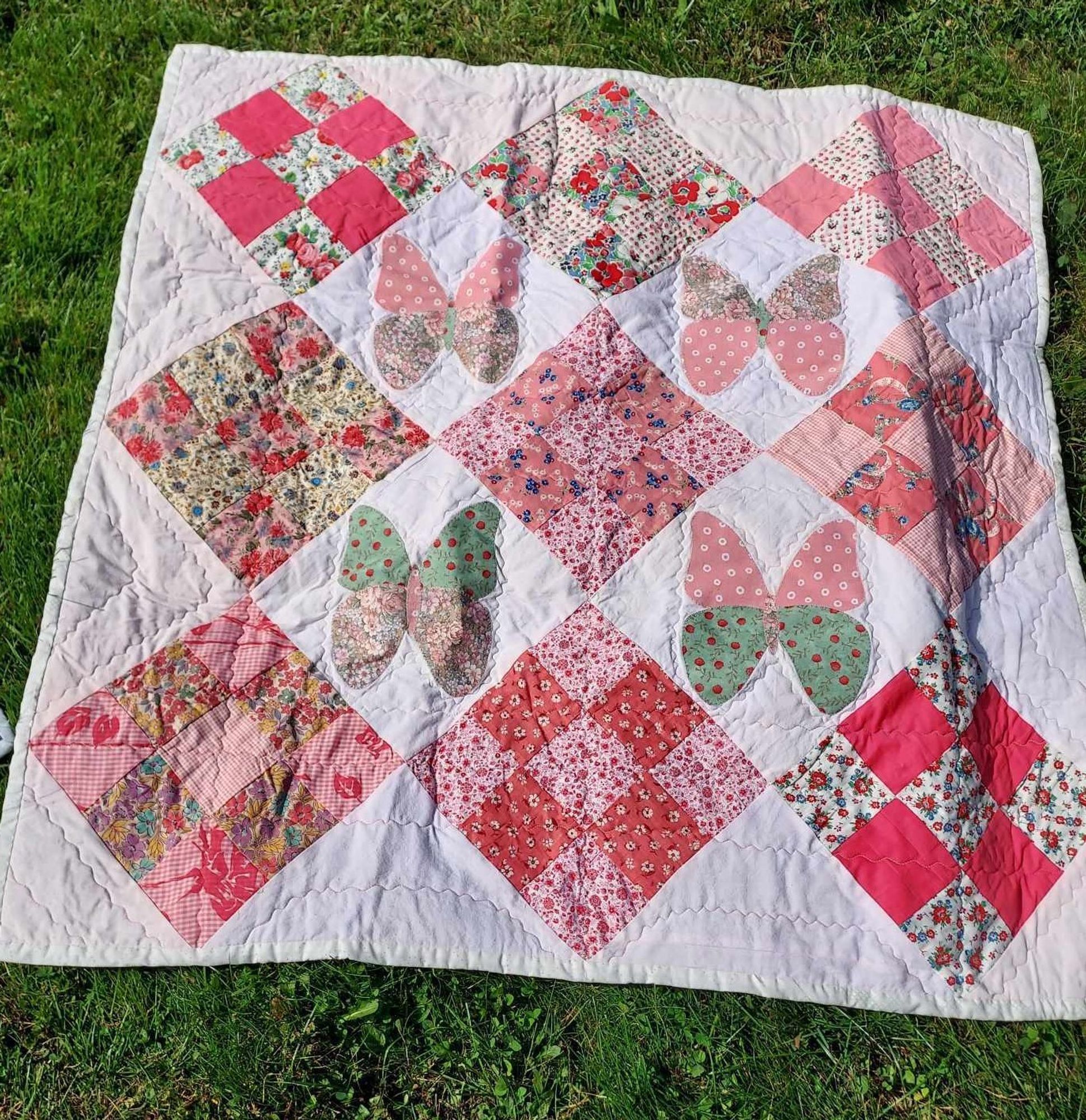 a quilt with pink diamonds and butterflies