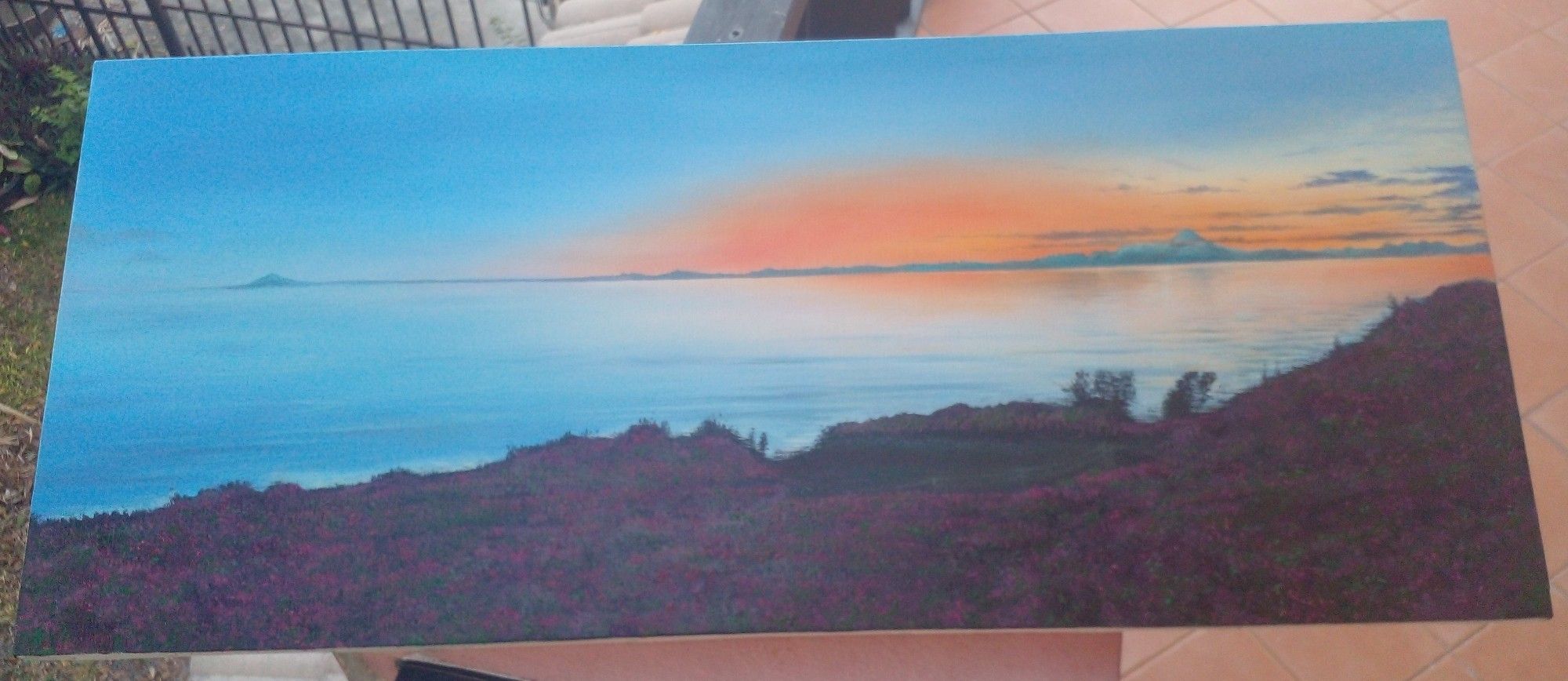 a painting, it is looking out onto a body of water, fireweed blooming in the evening light in the foreground, the orange sunset reflecting on the ocean, a quiet and tranquil and majestic scene