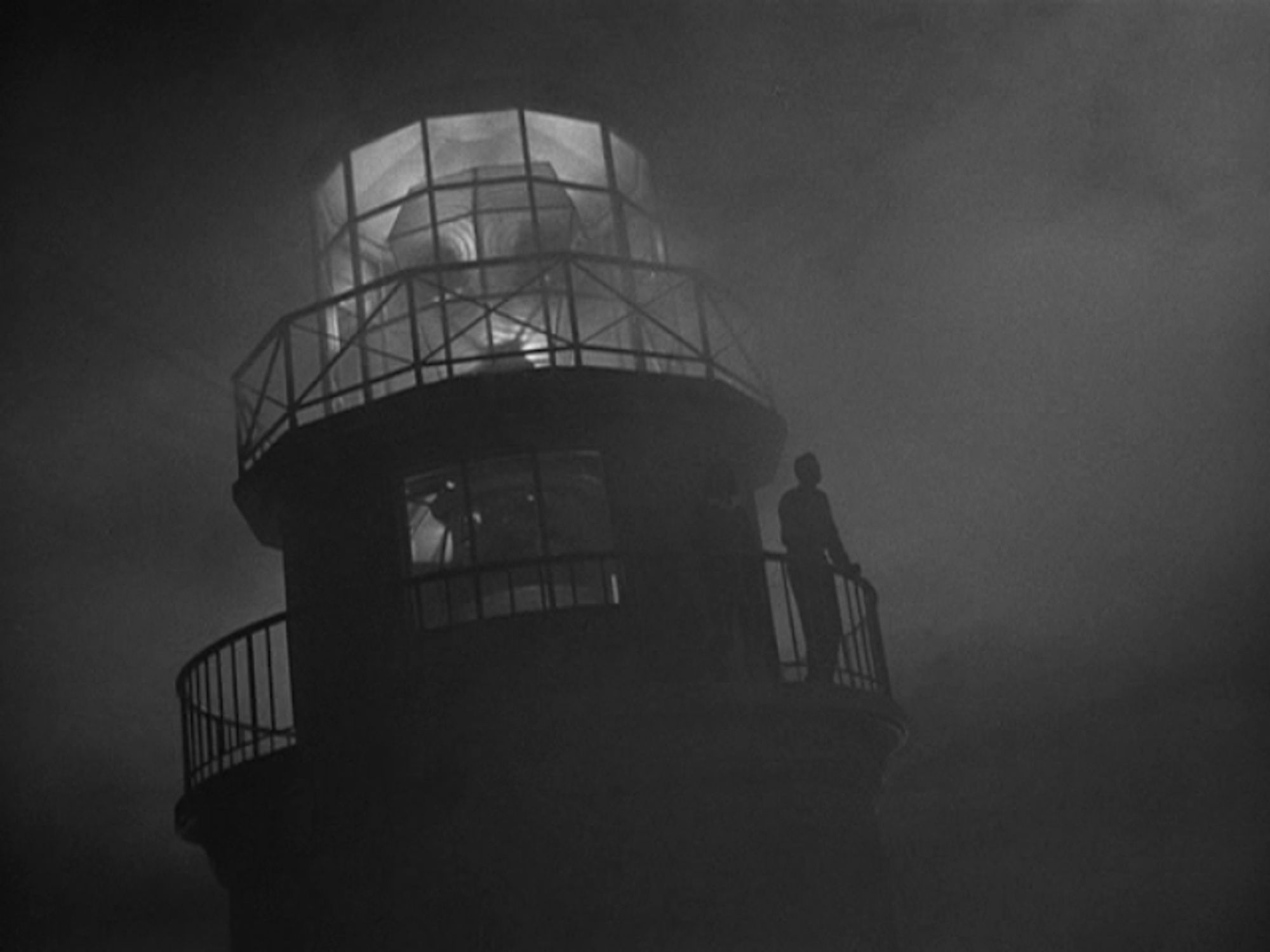 an image of the lighthouse at night in the fog, lit up