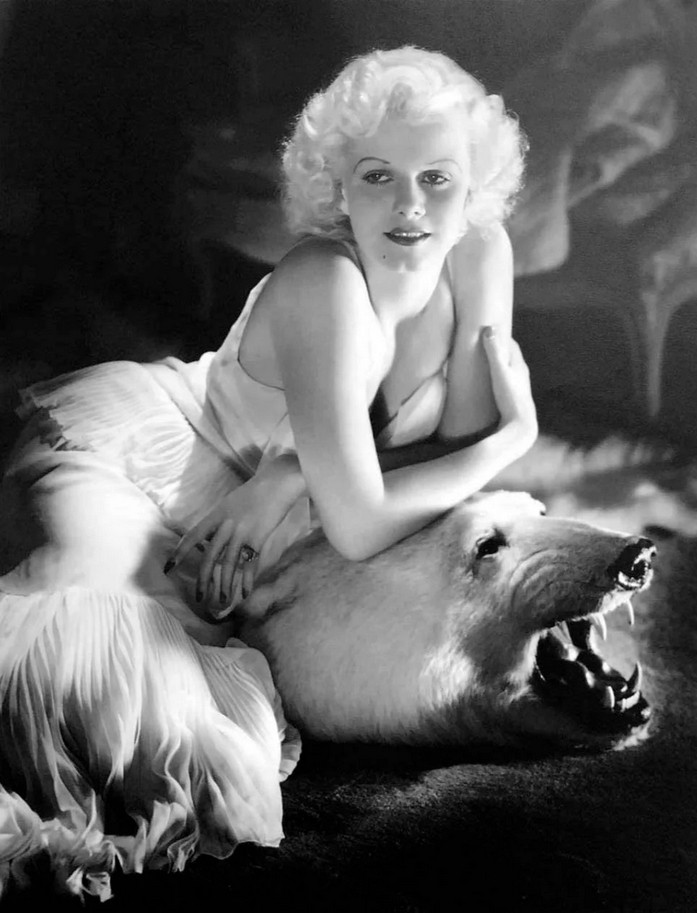 a  photo of the actress, black and white, she is leaning on the head of a polar bear, wearing a fashionable white dress, she is very blonde, her arms crossed, looking to the side, smiling slightly