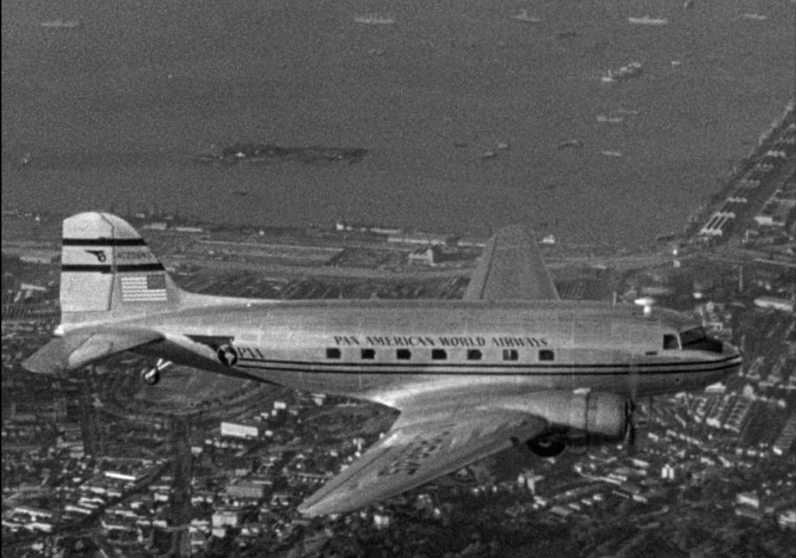 an image of a plane flying over a city next to a body of water