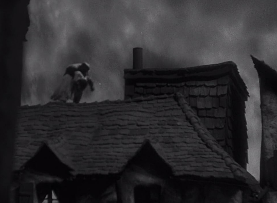 an image of a monstrous figure running on a rooftop of an old-timey european urban building