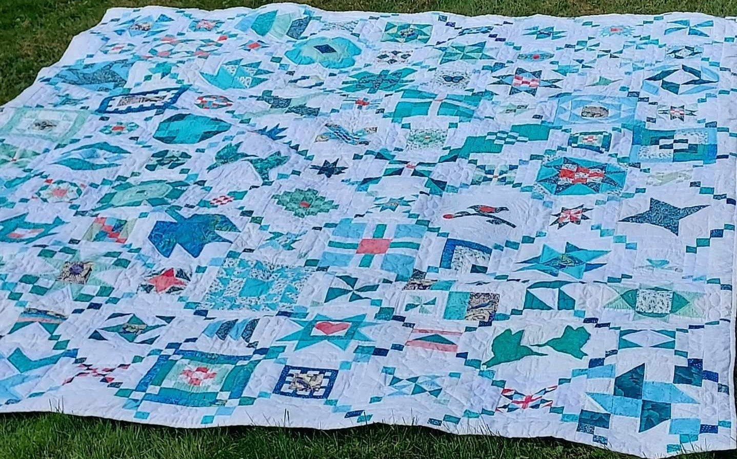 a quilt, it is teal and blue and green geometric shapes with some light red ones too