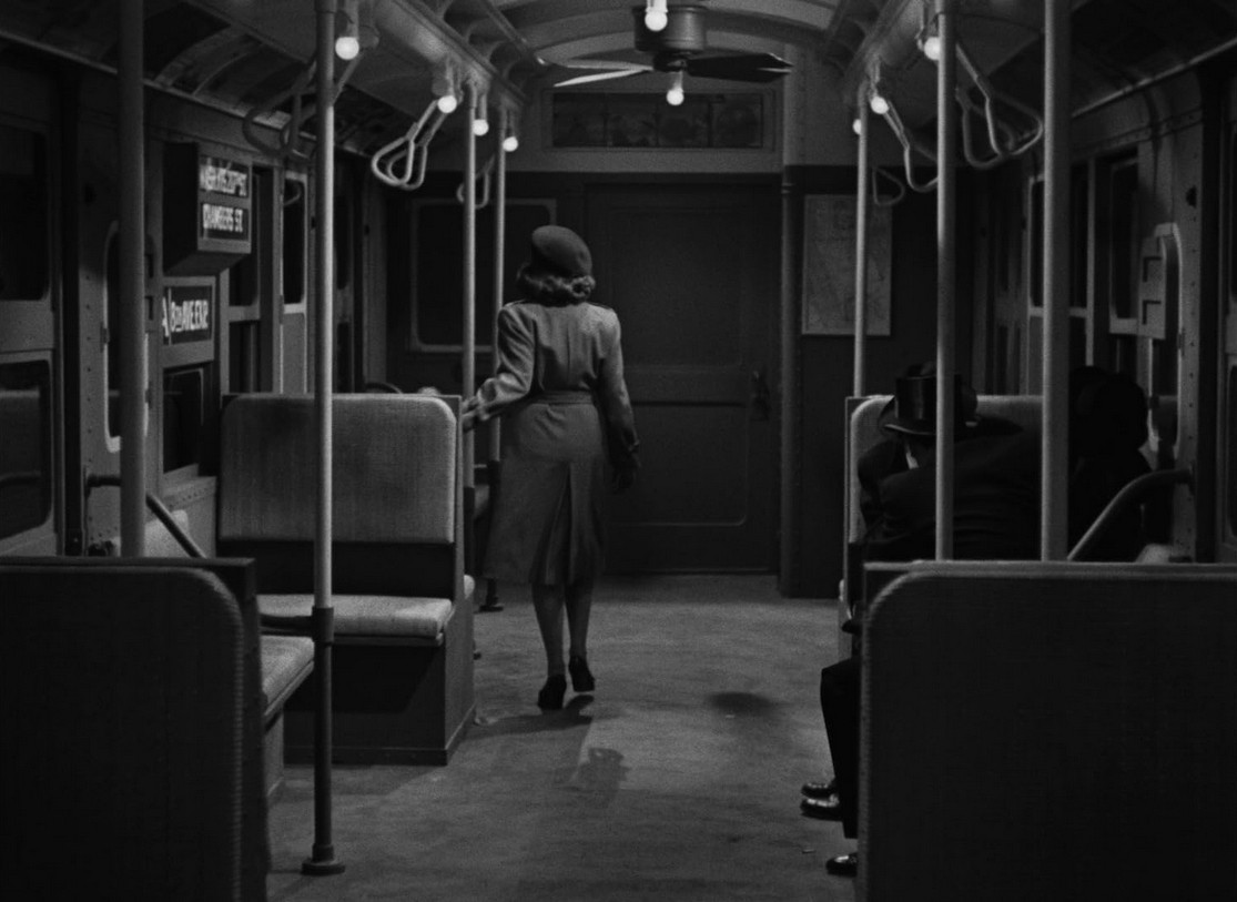 an image from the movie of a well-dressed woman seen from behind on an empty subway car