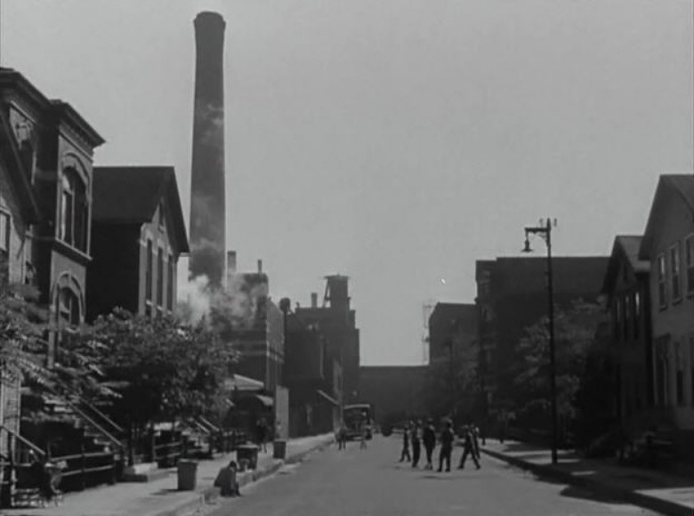 an image from the movie of a street scene, several figures running around in the middle of the street, seen from far away