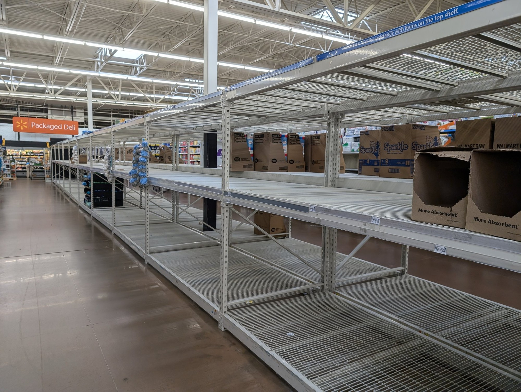 Empty shelves in Walmart where toilet paper and paper towels are usually stocked.